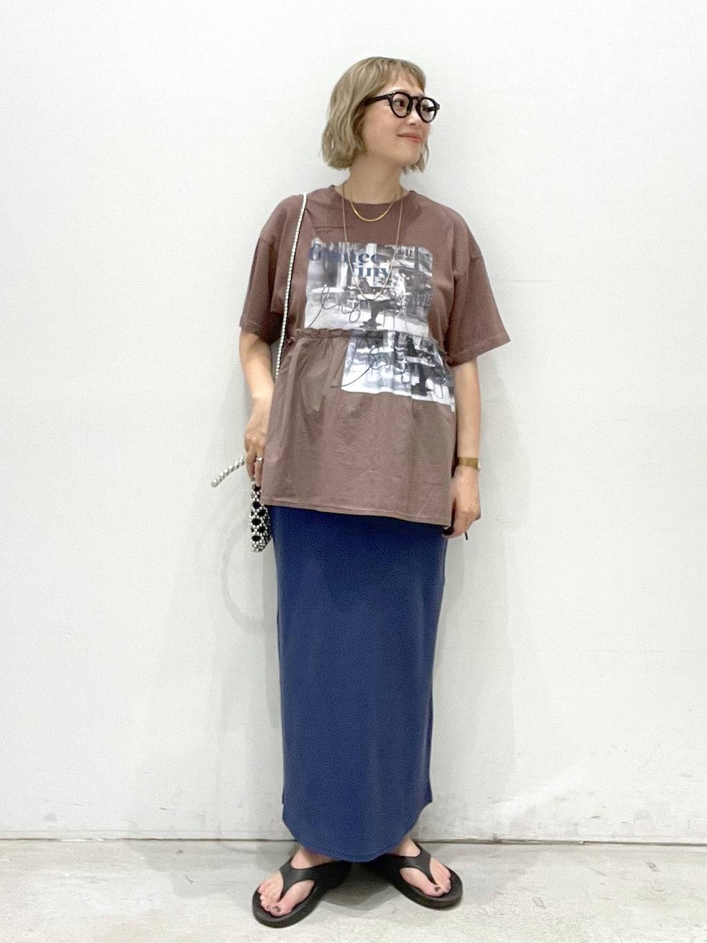 ブルー系のスカート、ブラウン系のTシャツ/カットソー、シルバー系のショルダーバッグを着用したレディースの夏コーディネートの4枚目の写真