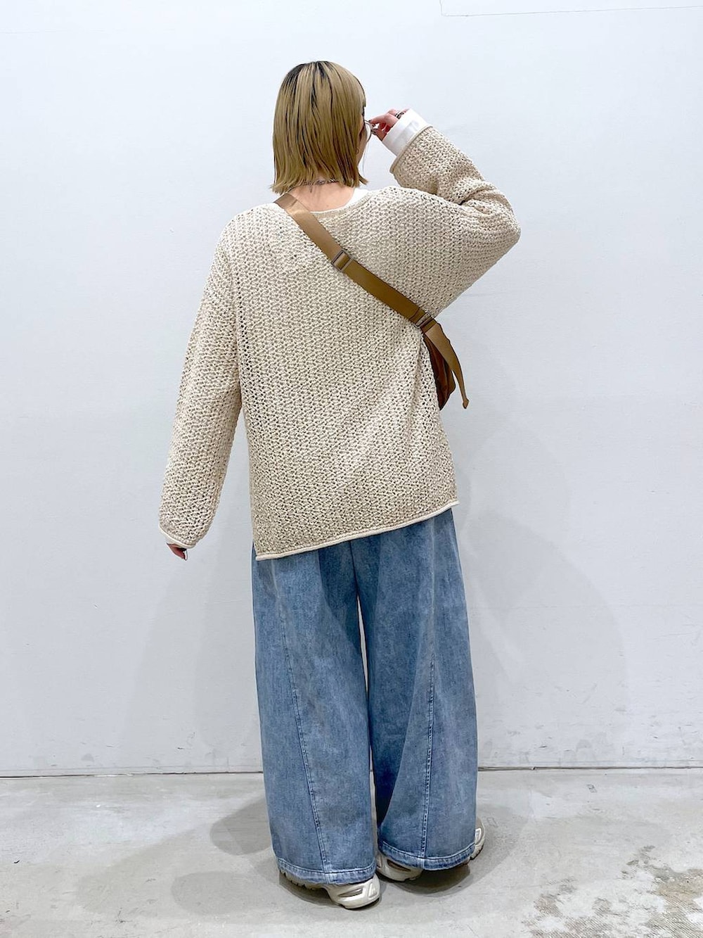ホワイト系のニット/セーター、ブルー系のデニムパンツ、ホワイト系のTシャツ/カットソーを着用したレディースの春コーディネートの3枚目の写真