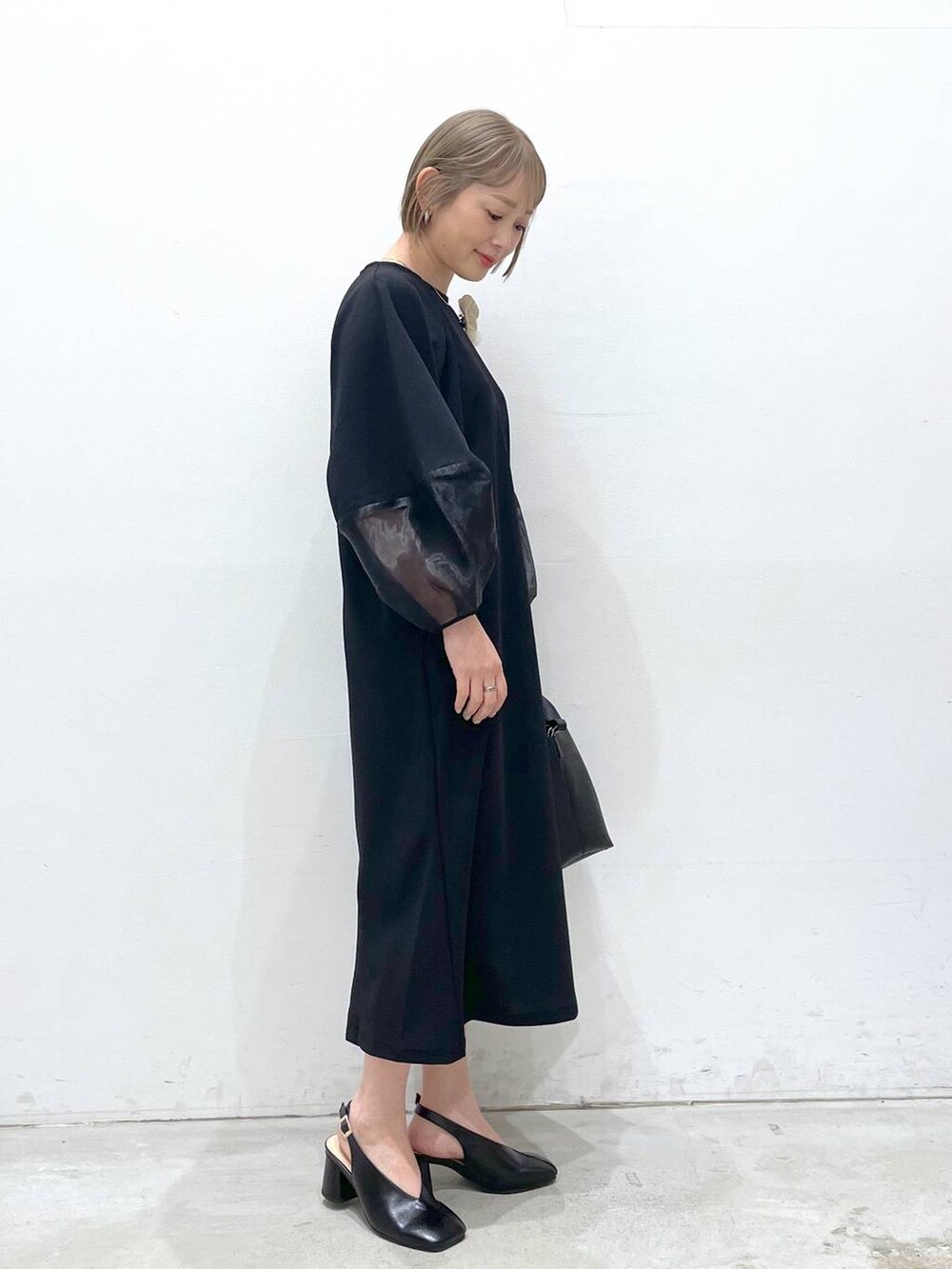 ブラック系のワンピース、ブラック系のパンプス、ブラック系のショルダーバッグを着用したレディースの冬コーディネートの2枚目の写真