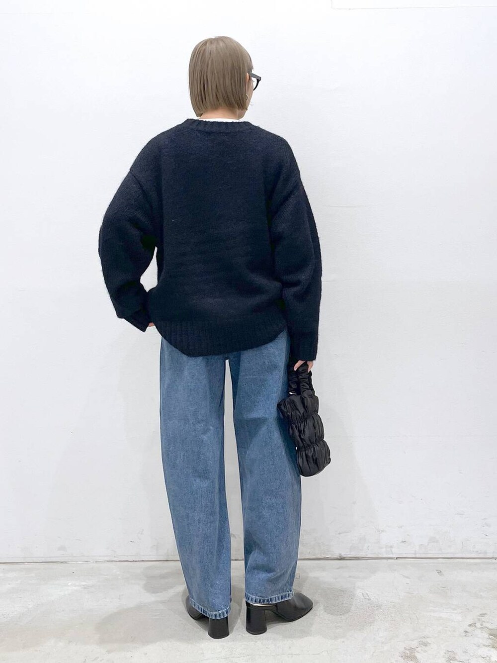 ブルー系のデニムパンツ、ブルー系のニット/セーター、ブラック系のショルダーバッグを着用したレディースの冬コーディネートの3枚目の写真