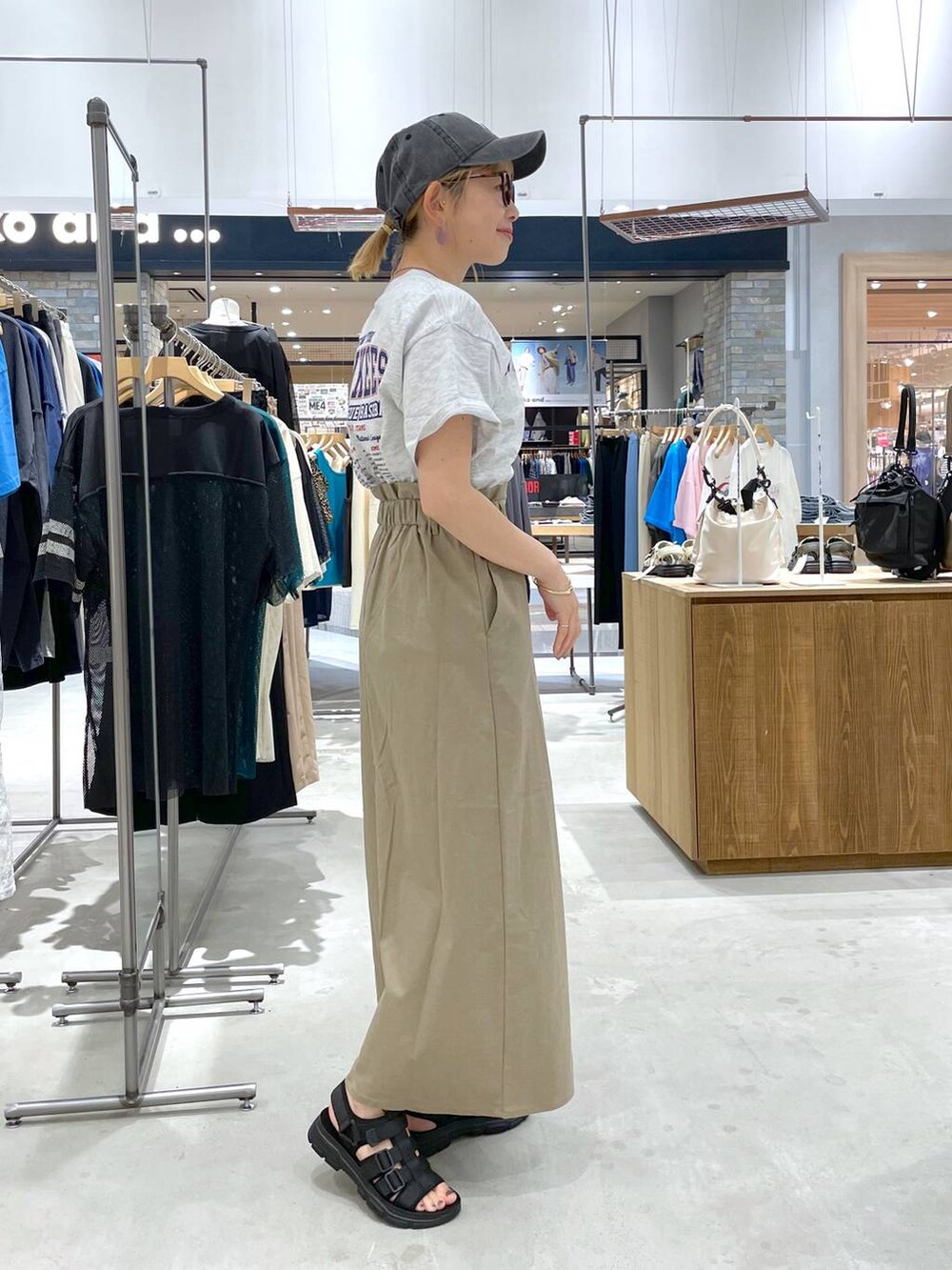 ブラック系のサンダル、ベージュ系のTシャツ/カットソー、グリーン系のスカートを着用したレディースの夏コーディネートの2枚目の写真