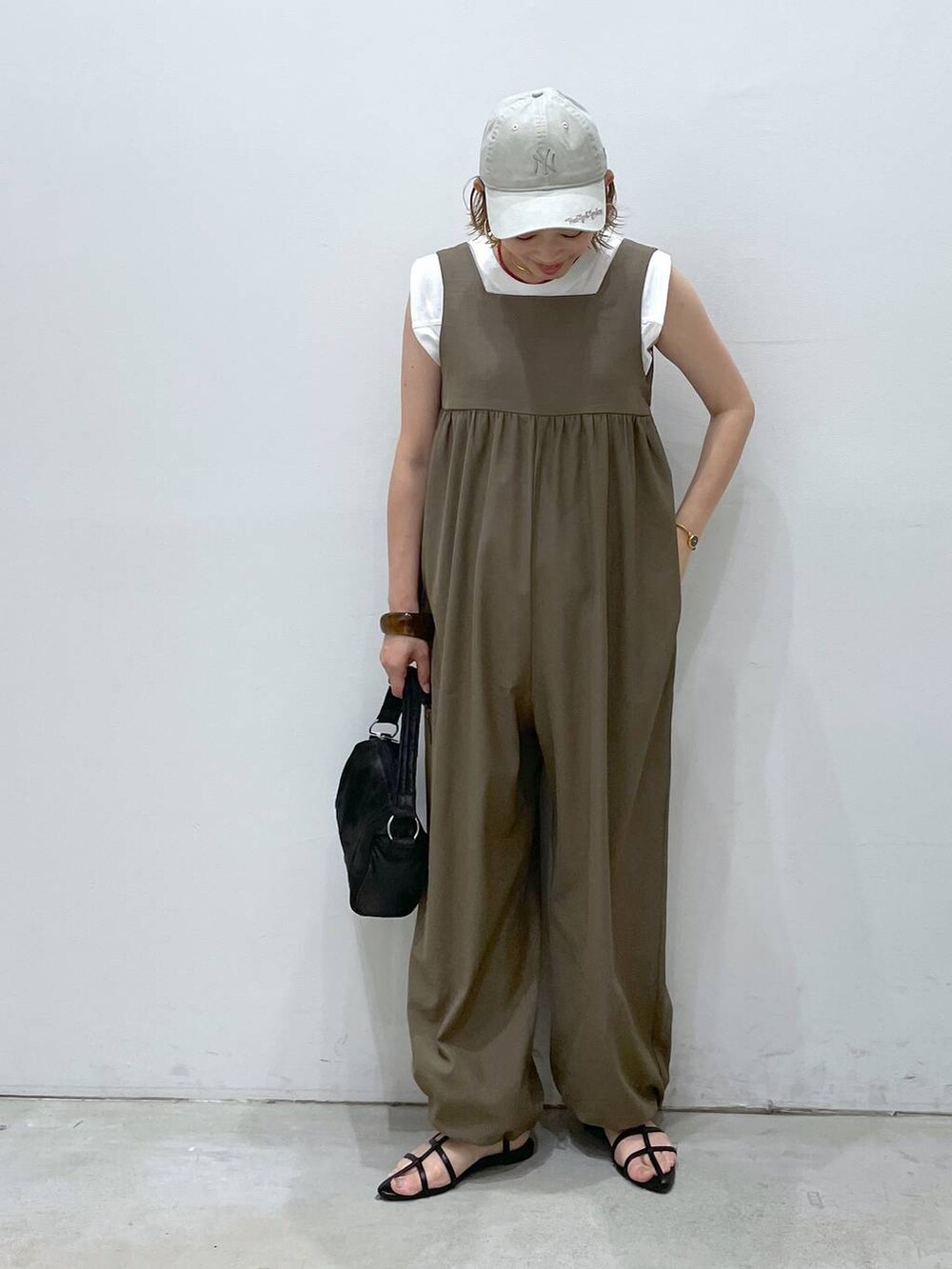 ブラック系のサンダル、イエロー系のつなぎ/オールインワン、ブラック系のハンドバッグを着用したレディースの夏コーディネートの4枚目の写真