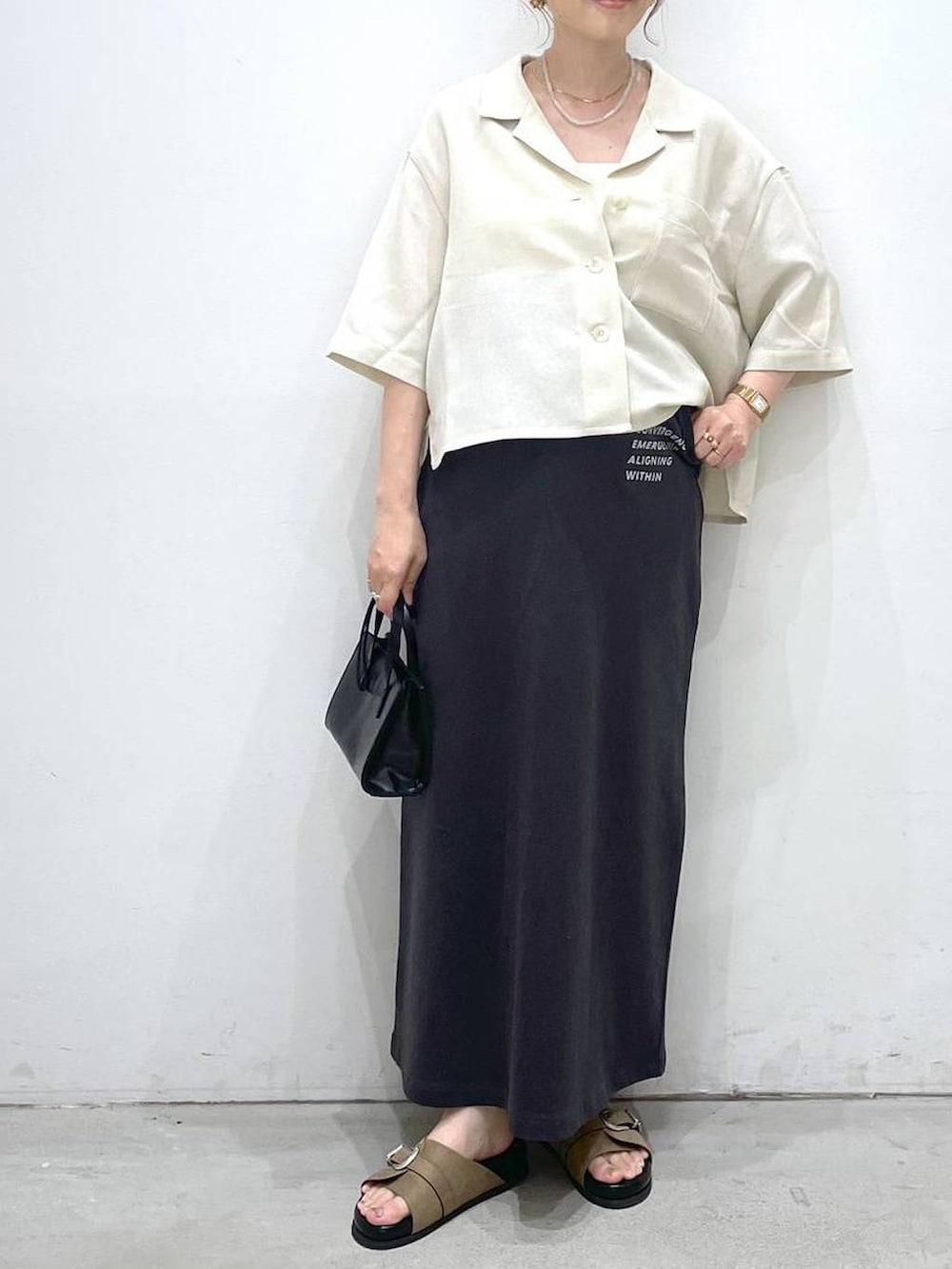 ブラック系のショルダーバッグ、グレー系のスカート、ベージュ系のシャツ/ブラウスを着用したレディースの夏コーディネートの4枚目の写真