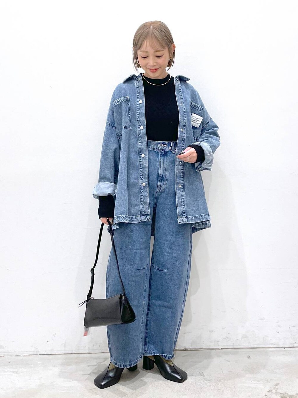 ブラック系のニット/セーター、ブルー系のデニムパンツ、ブラック系のパンプスを着用したレディースの冬コーディネートの4枚目の写真