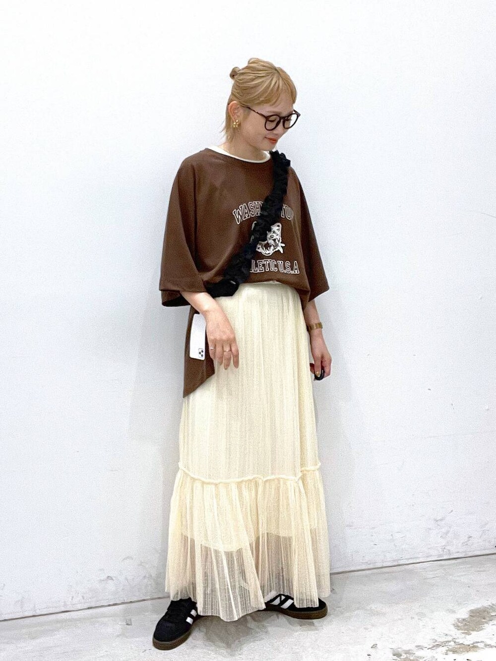 ホワイト系のタンクトップ、ブラック系のスニーカー、ブラック系のスマホグッズを着用したレディースの夏コーディネートの2枚目の写真