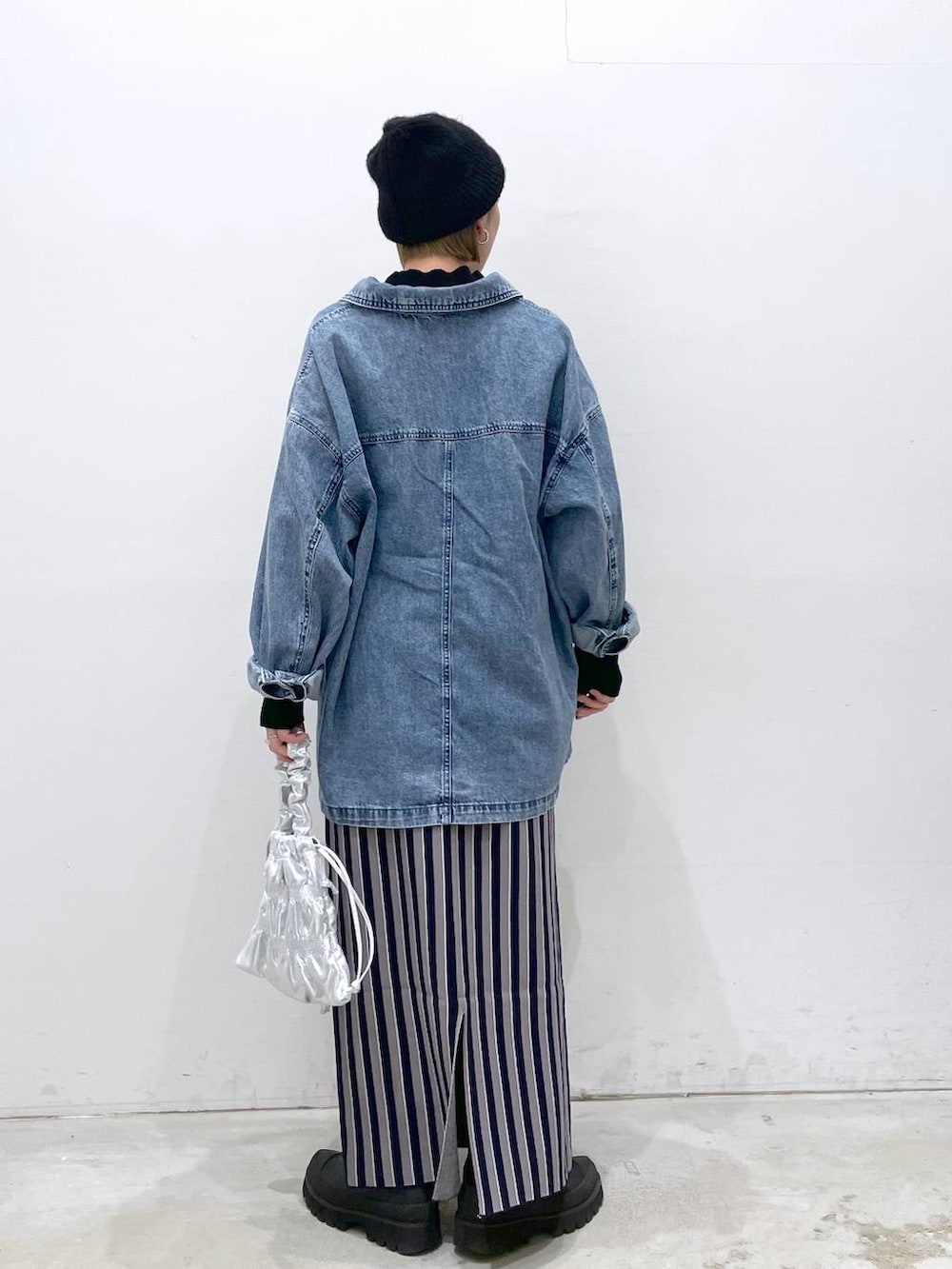 シルバー系のショルダーバッグ、ブルー系のスカート、ブラック系のニット/セーターを着用したレディースの冬コーディネートの3枚目の写真