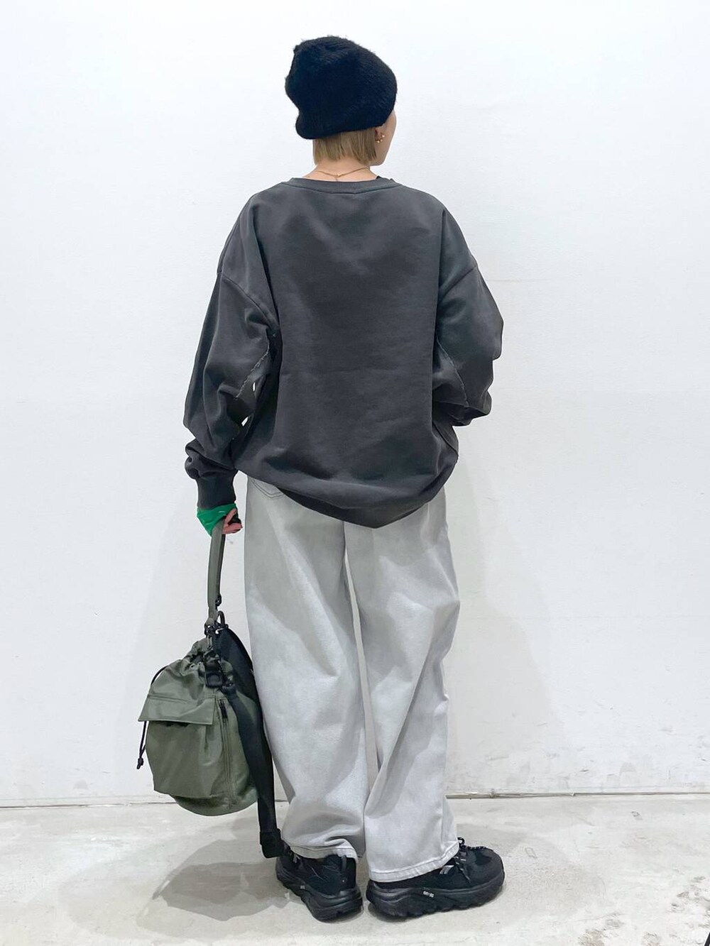 グリーン系のショルダーバッグ、ブラック系のTシャツ/カットソー、グレー系のデニムパンツを着用したレディースの冬コーディネートの3枚目の写真