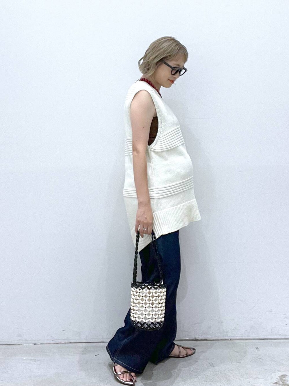 ブルー系のデニムパンツ、その他のサンダル、ホワイト系のハンドバッグを着用したレディースの夏コーディネートの2枚目の写真