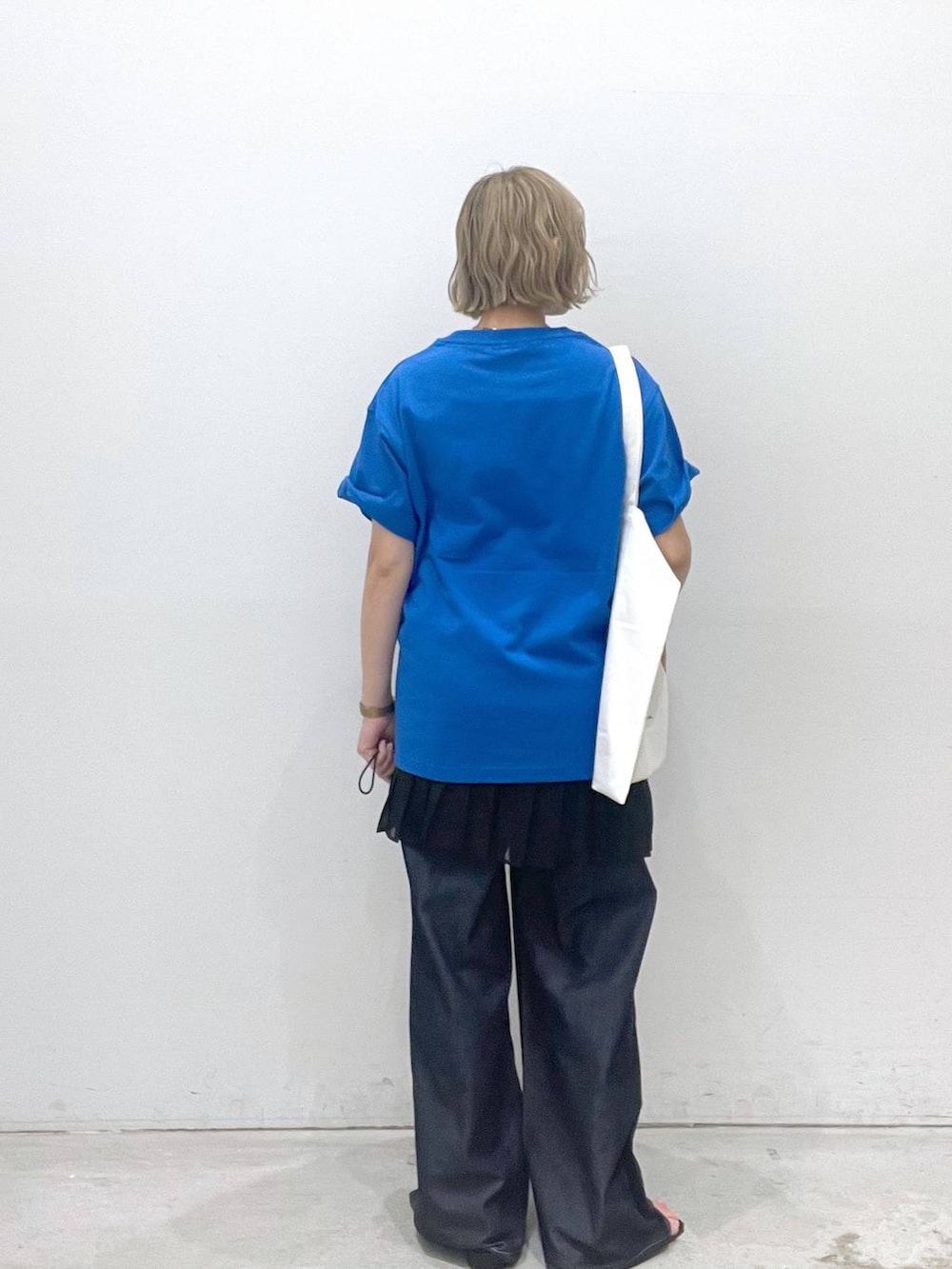 ブルー系のデニムパンツ、ブラック系のスカート、ブラック系のサンダルを着用したレディースの夏コーディネートの3枚目の写真