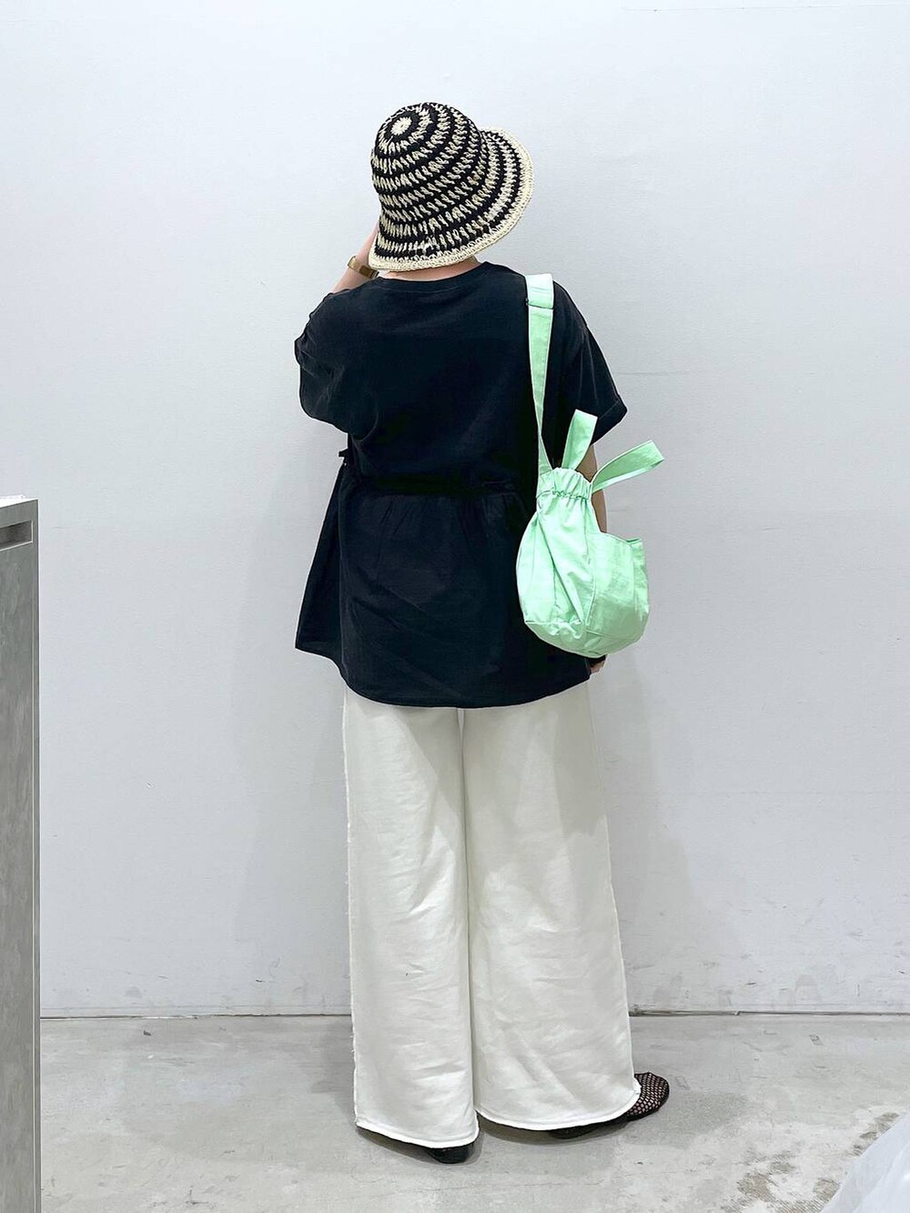 ホワイト系のスウェットパンツ、ブラック系のパンプス、グリーン系のショルダーバッグを着用したレディースの春コーディネートの3枚目の写真