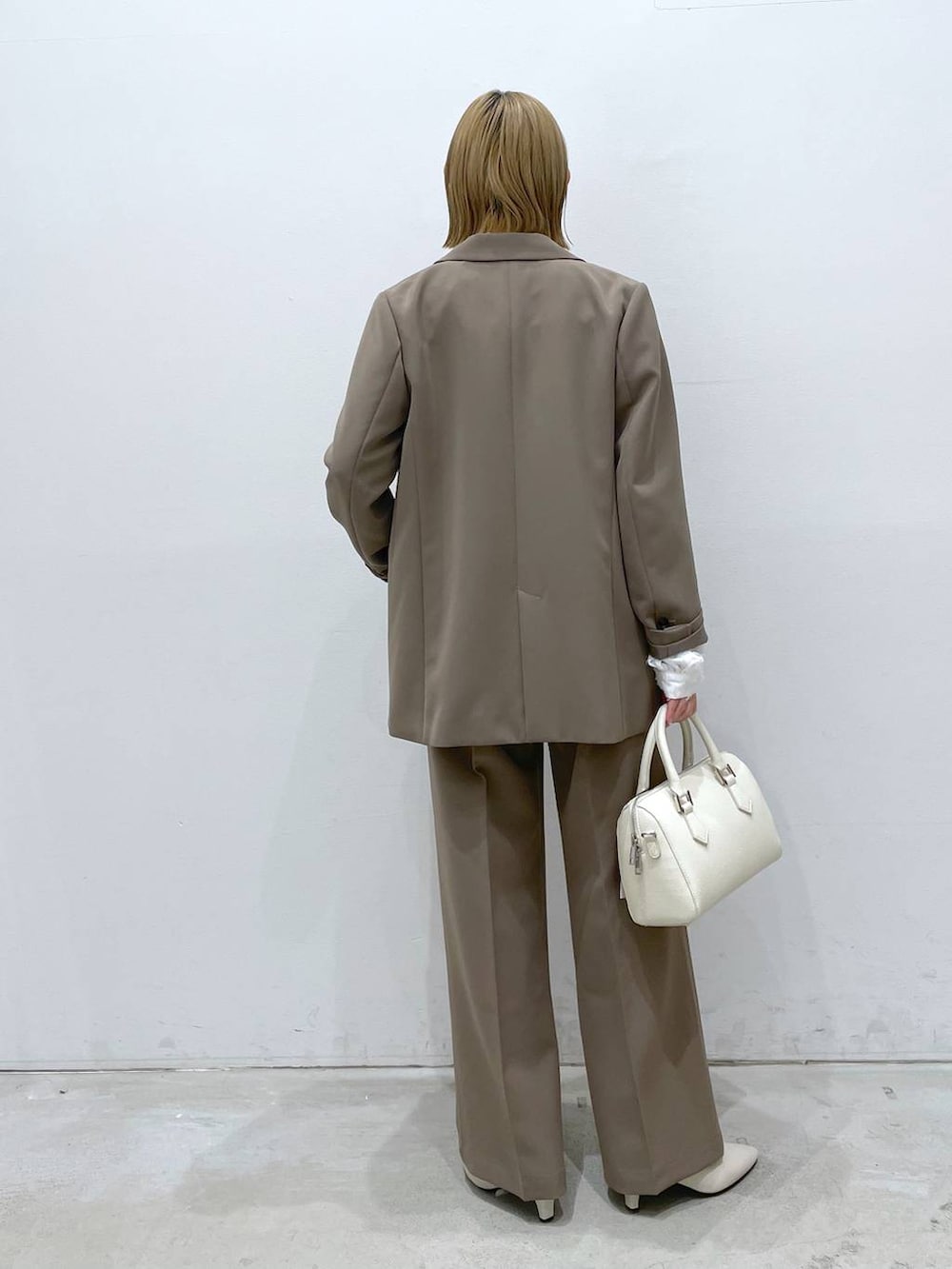 ブラウン系のスーツパンツ、ホワイト系のシャツ/ブラウス、ホワイト系のパンプスを着用したレディースの冬コーディネートの3枚目の写真