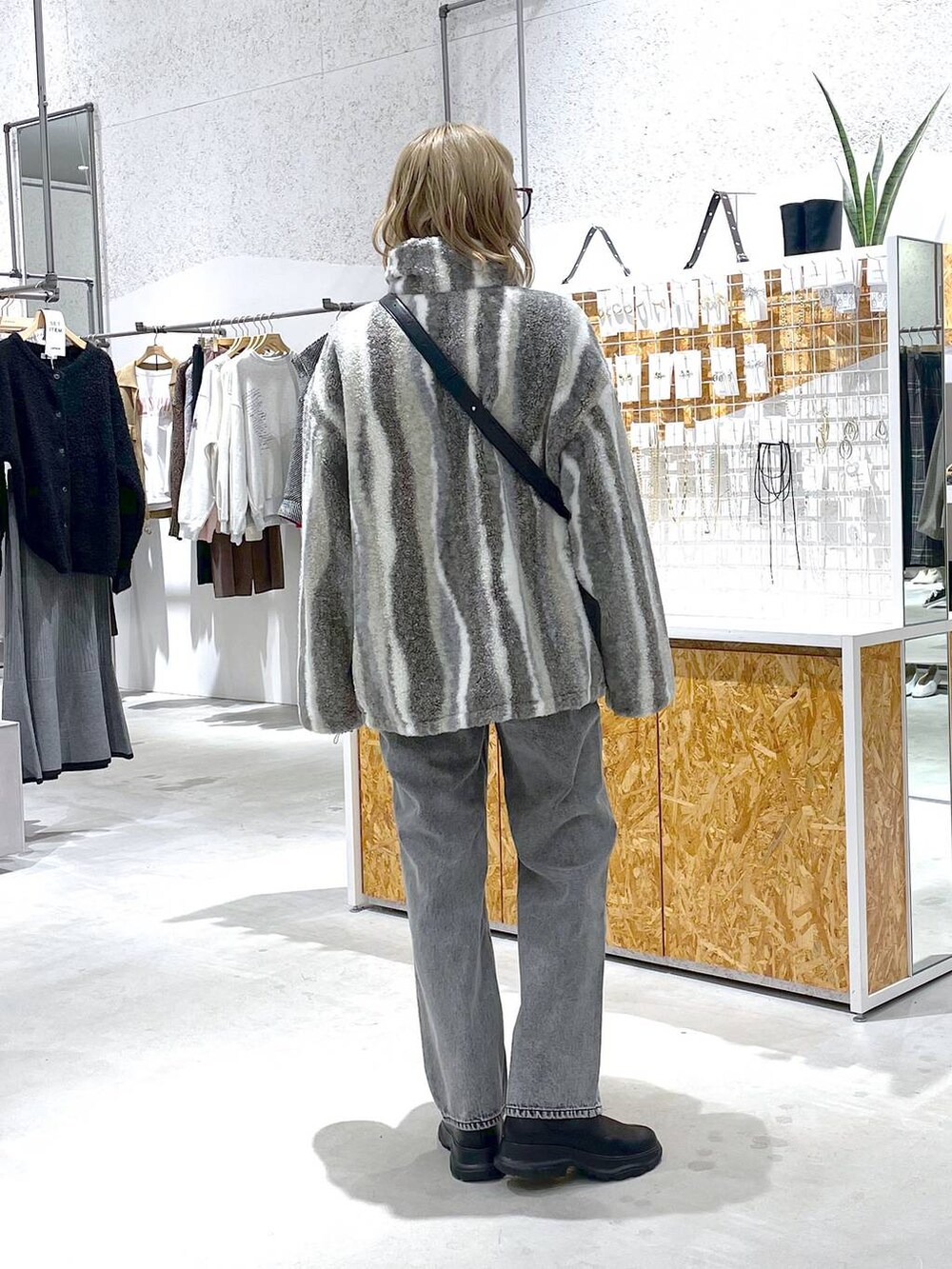 ブラック系のショルダーバッグ、ホワイト系のブルゾン、グレー系のデニムパンツを着用したレディースの秋コーディネートの3枚目の写真