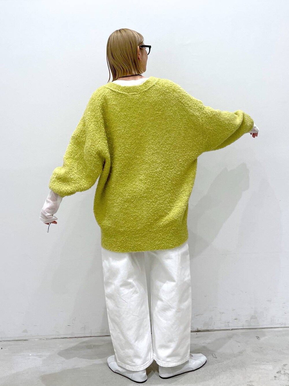 ホワイト系のデニムパンツ、シルバー系のバレエシューズ、イエロー系のカーディガン/ボレロを着用したレディースの冬コーディネートの3枚目の写真