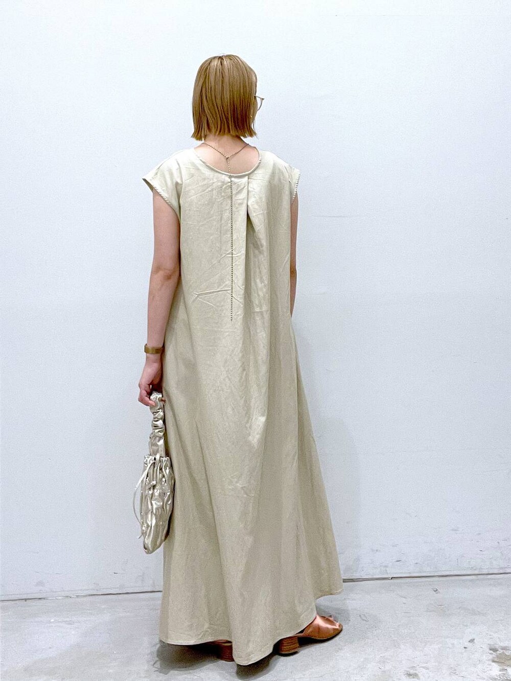 ホワイト系のワンピース、ホワイト系のタンクトップ、ゴールド系のショルダーバッグを着用したレディースの夏コーディネートの3枚目の写真