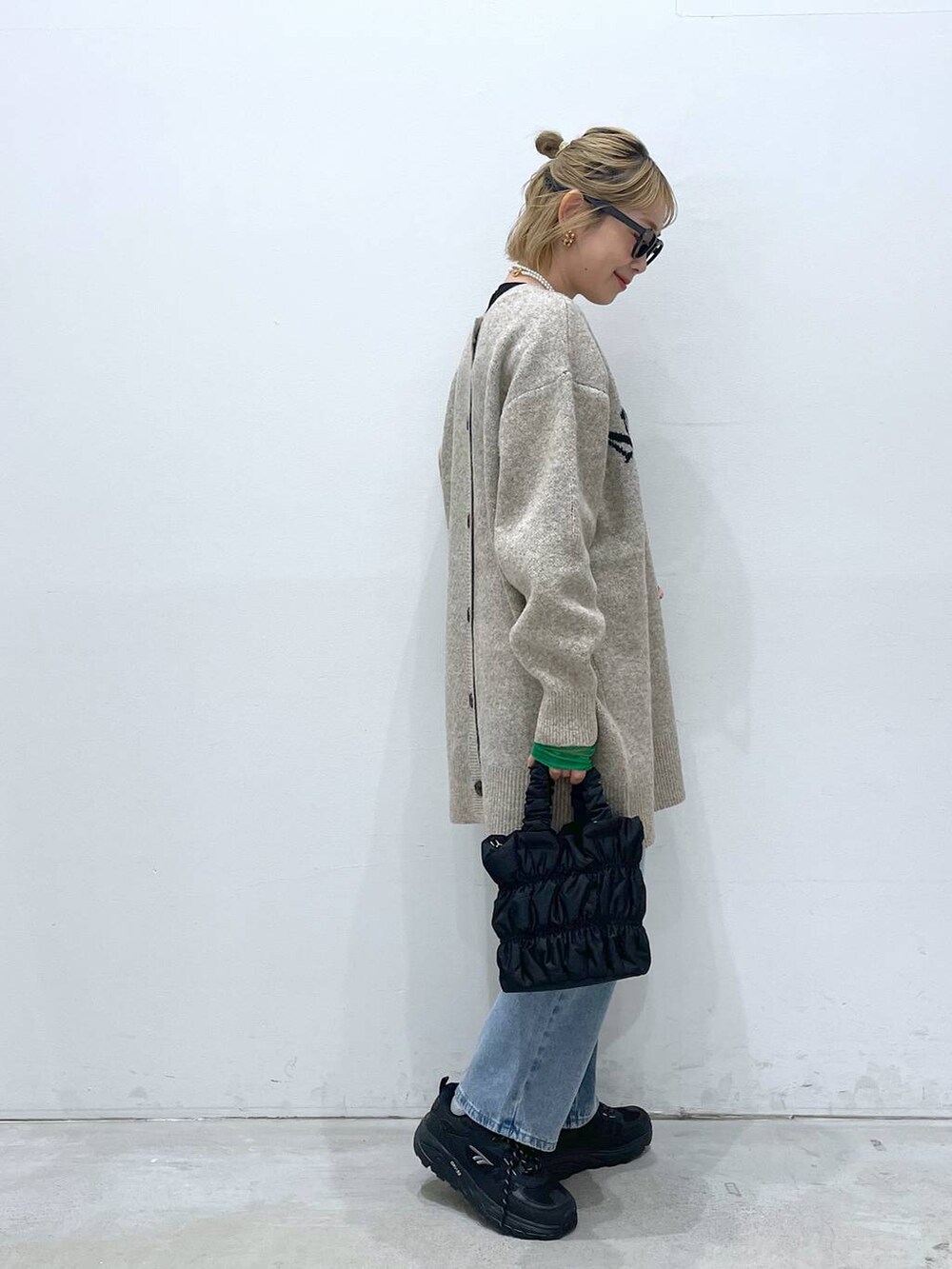 ブルー系のデニムパンツ、ブラック系のTシャツ/カットソー、ブラック系のショルダーバッグを着用したレディースの冬コーディネートの2枚目の写真