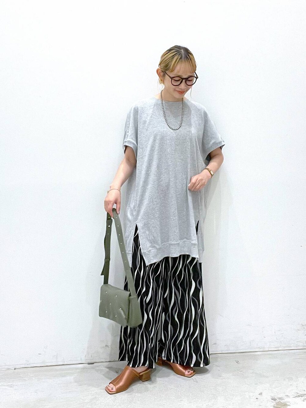 グリーン系のショルダーバッグ、ブラック系のその他パンツ、グレー系のチュニックを着用したレディースの夏コーディネートの4枚目の写真