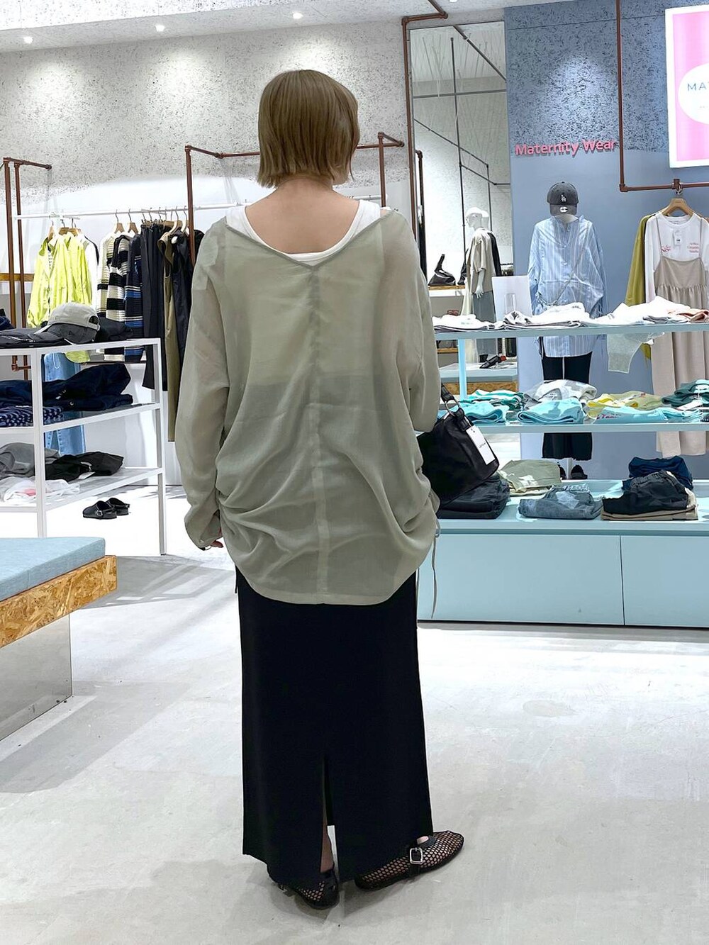 ブラック系のスカート、グリーン系のチュニック、ブラック系のパンプスを着用したレディースの春コーディネートの3枚目の写真