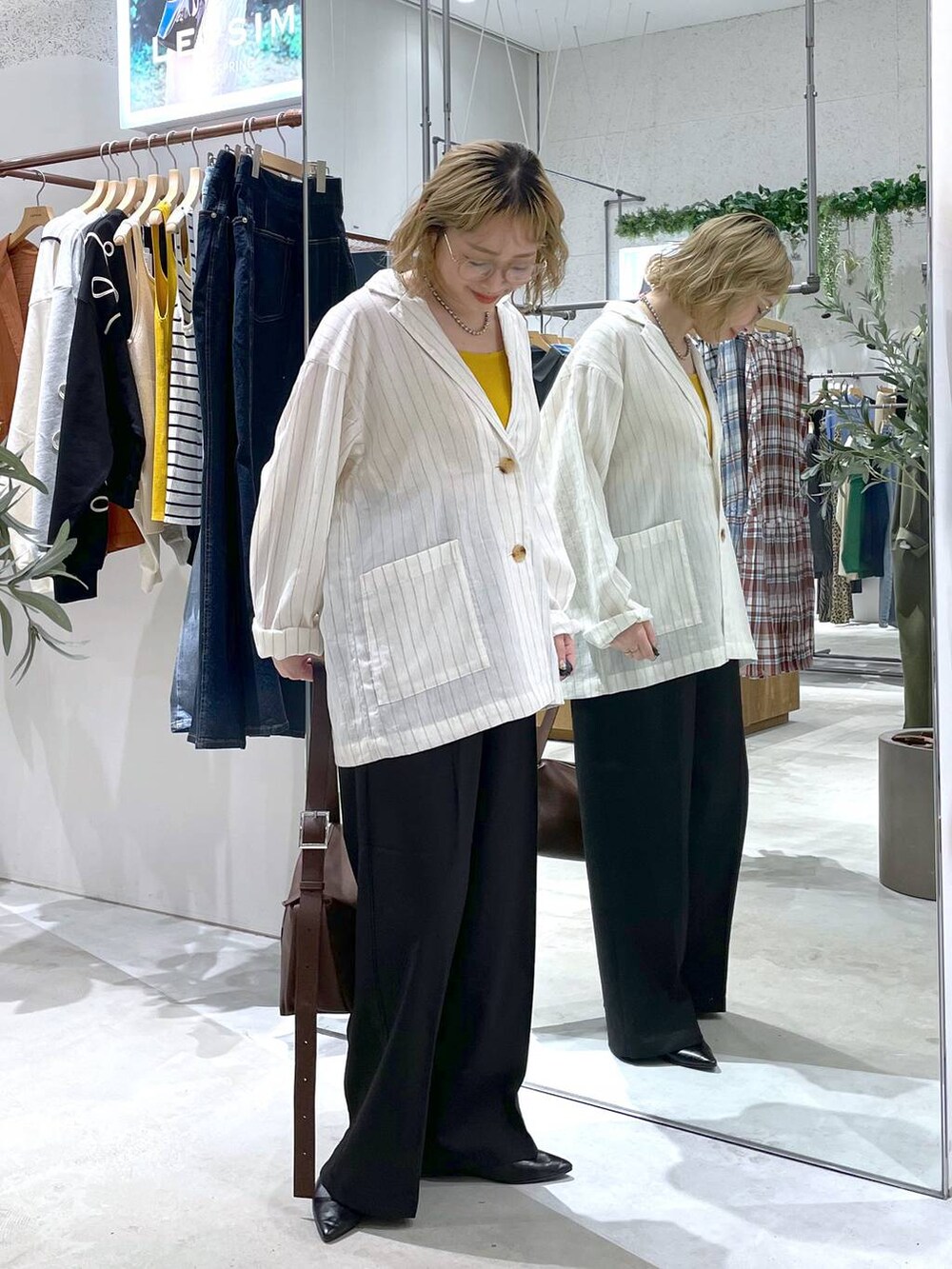 ブラウン系のショルダーバッグ、イエロー系のタンクトップ、ブラック系のその他パンツを着用したレディースの春コーディネートの2枚目の写真