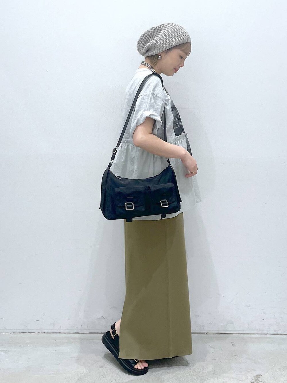 グリーン系のスカート、ブラック系のショルダーバッグ、ブラック系のサンダルを着用したレディースの春コーディネートの2枚目の写真