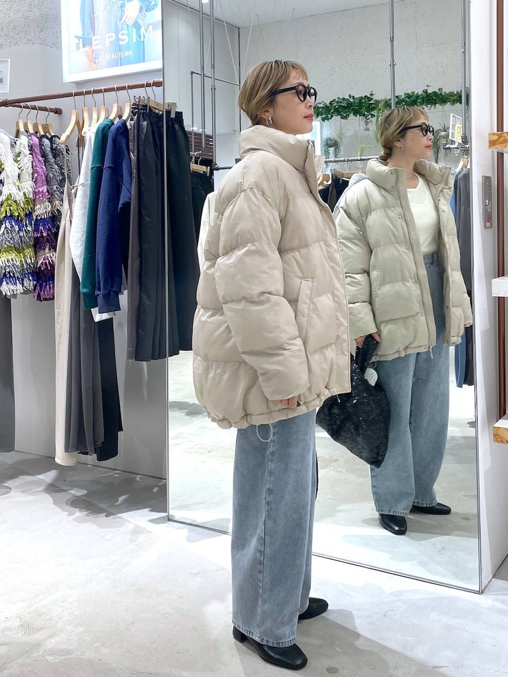 ベージュ系のダウンジャケット/コート、ブラック系のブーツ、ブルー系のデニムパンツを着用したレディースの秋コーディネートの2枚目の写真