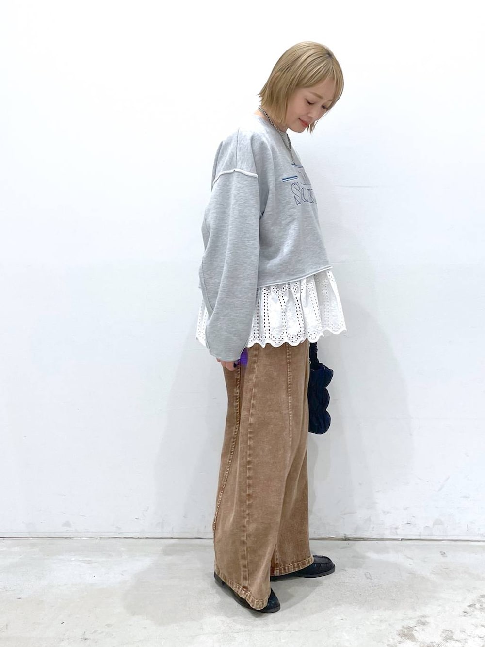 ホワイト系のTシャツ/カットソー、ブルー系のショルダーバッグ、ブラウン系のデニムパンツを着用したレディースの冬コーディネートの3枚目の写真