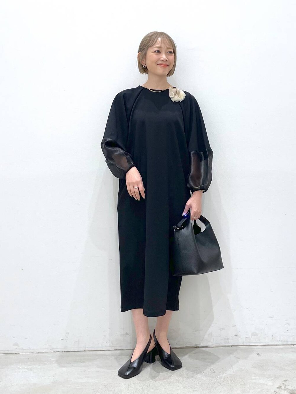 ブラック系のワンピース、ブラック系のパンプス、ブラック系のショルダーバッグを着用したレディースの冬コーディネートの4枚目の写真