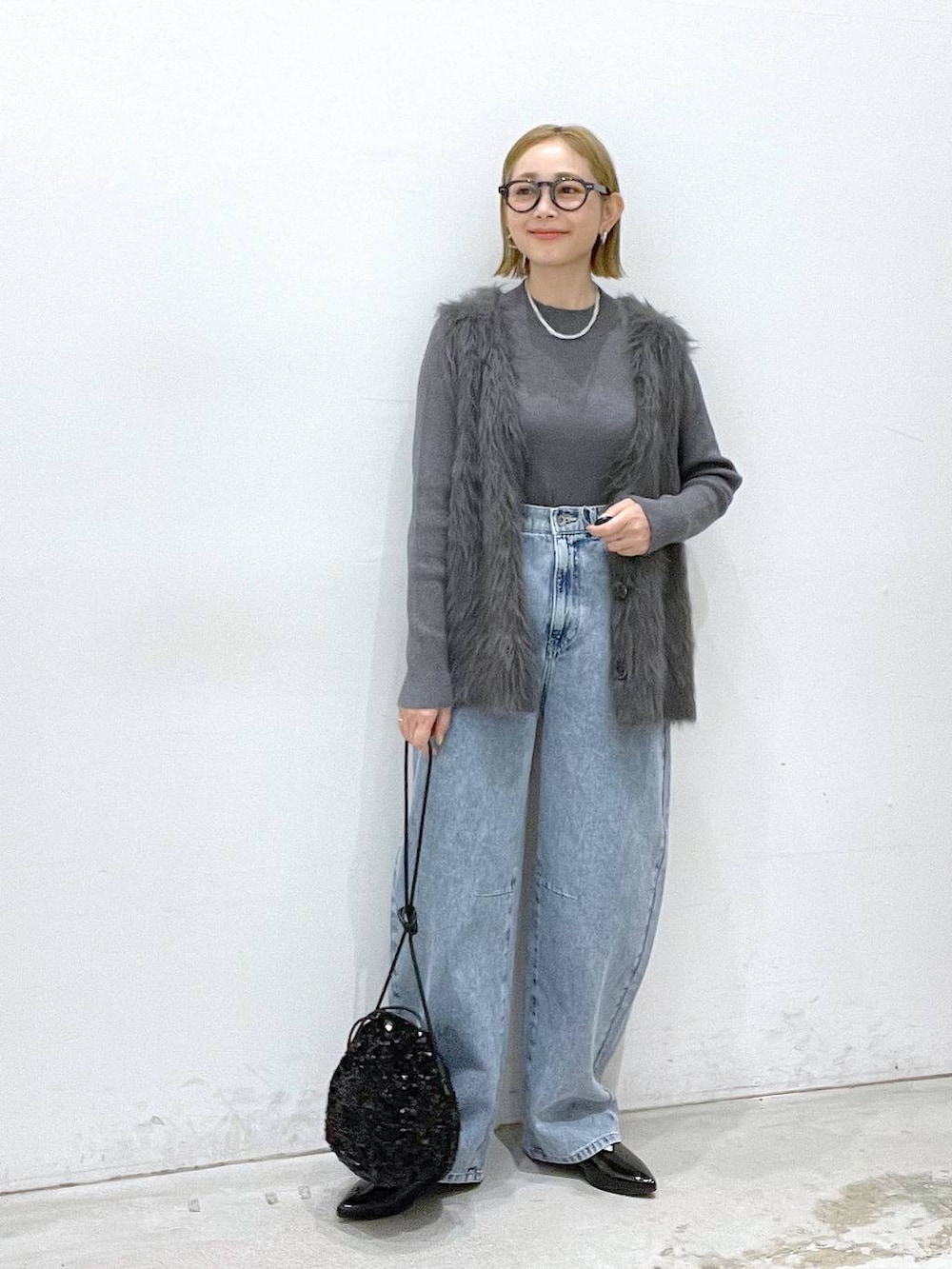 ブラック系のその他シューズ、ブラック系のショルダーバッグ、グレー系のベストを着用したレディースの秋コーディネートの4枚目の写真