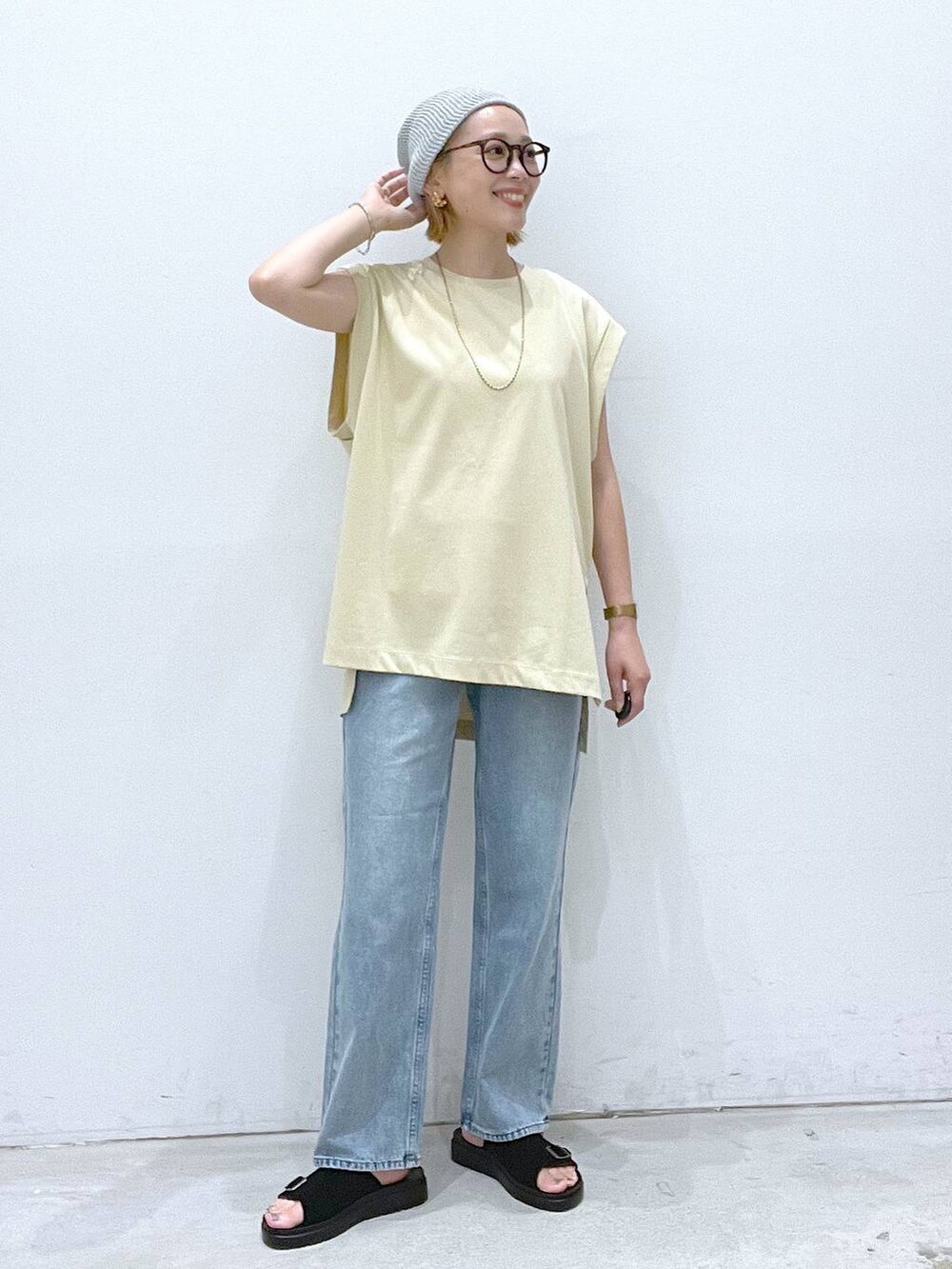 ベージュ系のTシャツ/カットソー、ブラック系のサンダル、ホワイト系のタンクトップを着用したレディースの夏コーディネートの4枚目の写真