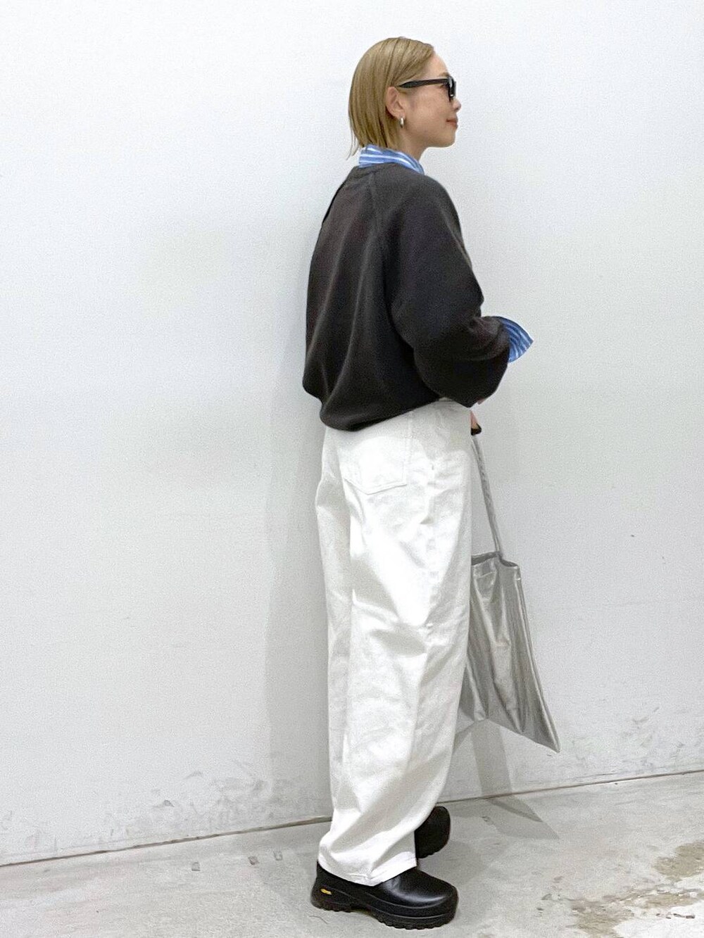 シルバー系のトートバッグ、グレー系のニット/セーター、ホワイト系のデニムパンツを着用したレディースの冬コーディネートの3枚目の写真