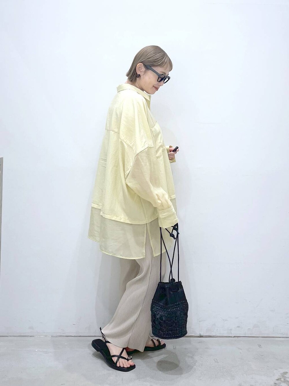 ブラック系のショルダーバッグ、イエロー系のシャツ/ブラウス、ベージュ系のその他パンツを着用したレディースの夏コーディネートの2枚目の写真