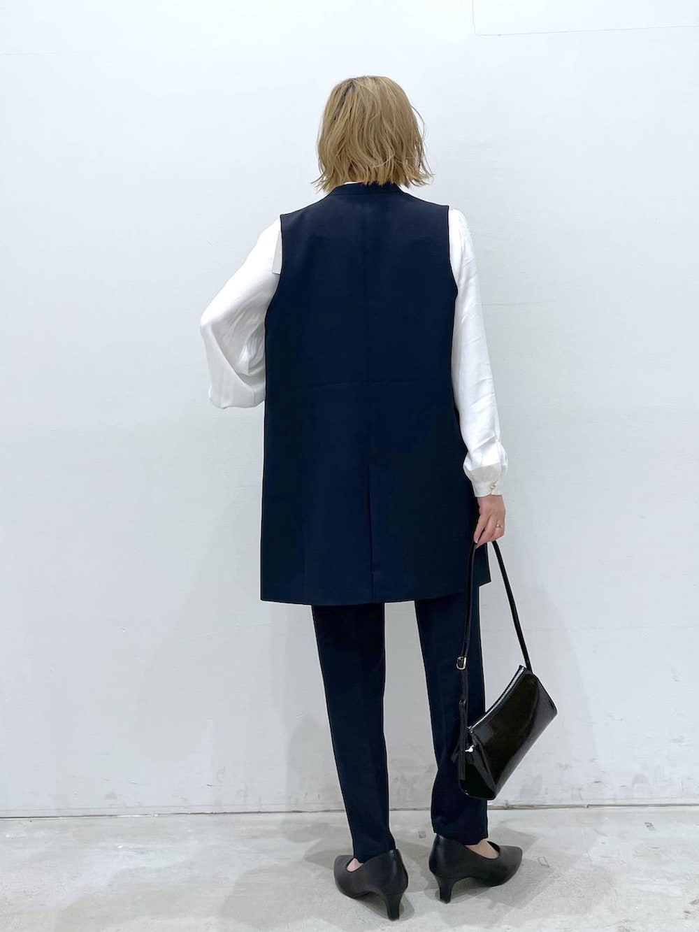 ブルー系のスーツパンツ、ホワイト系のシャツ/ブラウス、ブルー系のスーツベストを着用したレディースの冬コーディネートの3枚目の写真