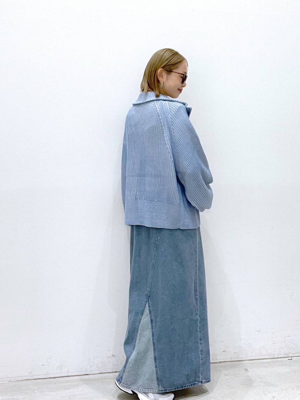 ブルー系のカーディガン/ボレロ、グレー系のスニーカー、ブルー系のジャンパースカートを着用したレディースの秋コーディネートの2枚目の写真