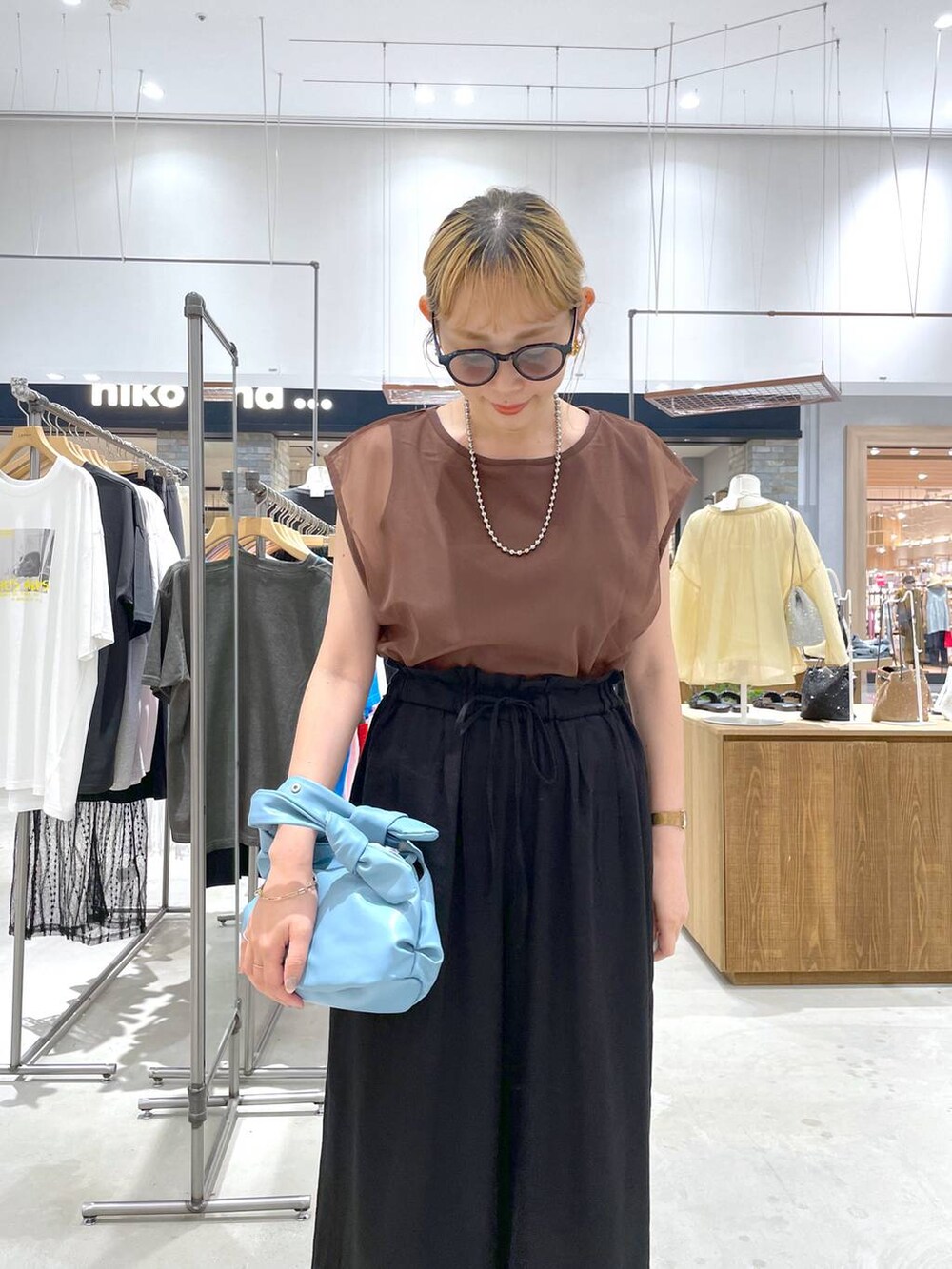 ブラック系のその他パンツ、ブルー系のショルダーバッグ、ブラウン系のTシャツ/カットソーを着用したレディースの夏コーディネートの2枚目の写真