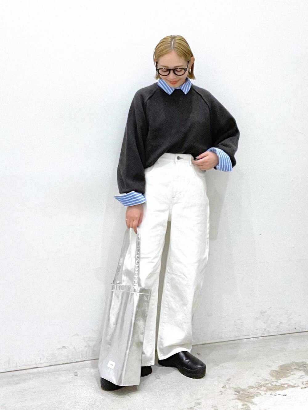 シルバー系のトートバッグ、グレー系のニット/セーター、ホワイト系のデニムパンツを着用したレディースの冬コーディネートの2枚目の写真