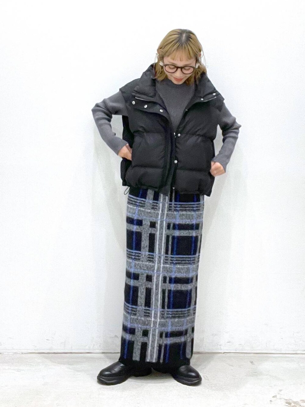 ブラック系のダウンベスト、ブラック系のブーツ、グレー系のニット/セーターを着用したレディースの秋コーディネートの3枚目の写真