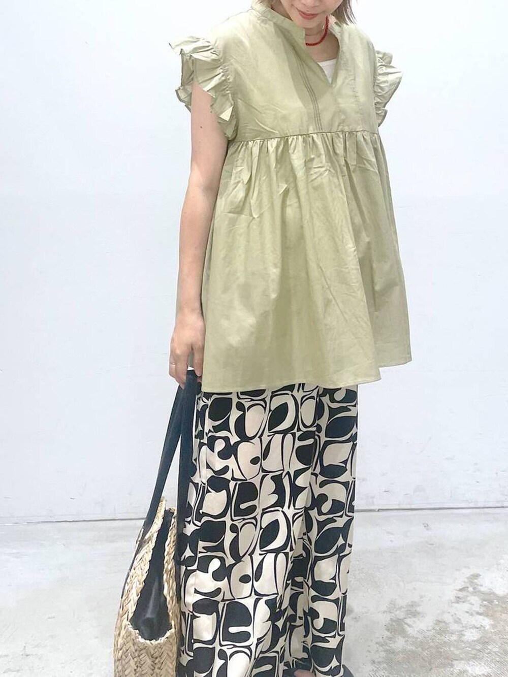 ホワイト系のタンクトップ、ブラック系のショルダーバッグ、ベージュ系のシャツ/ブラウスを着用したレディースの夏コーディネートの5枚目の写真