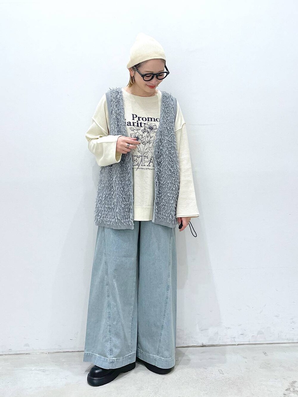 ブルー系のデニムパンツ、ブラック系のサンダル、グレー系のベストを着用したレディースの春コーディネートの4枚目の写真