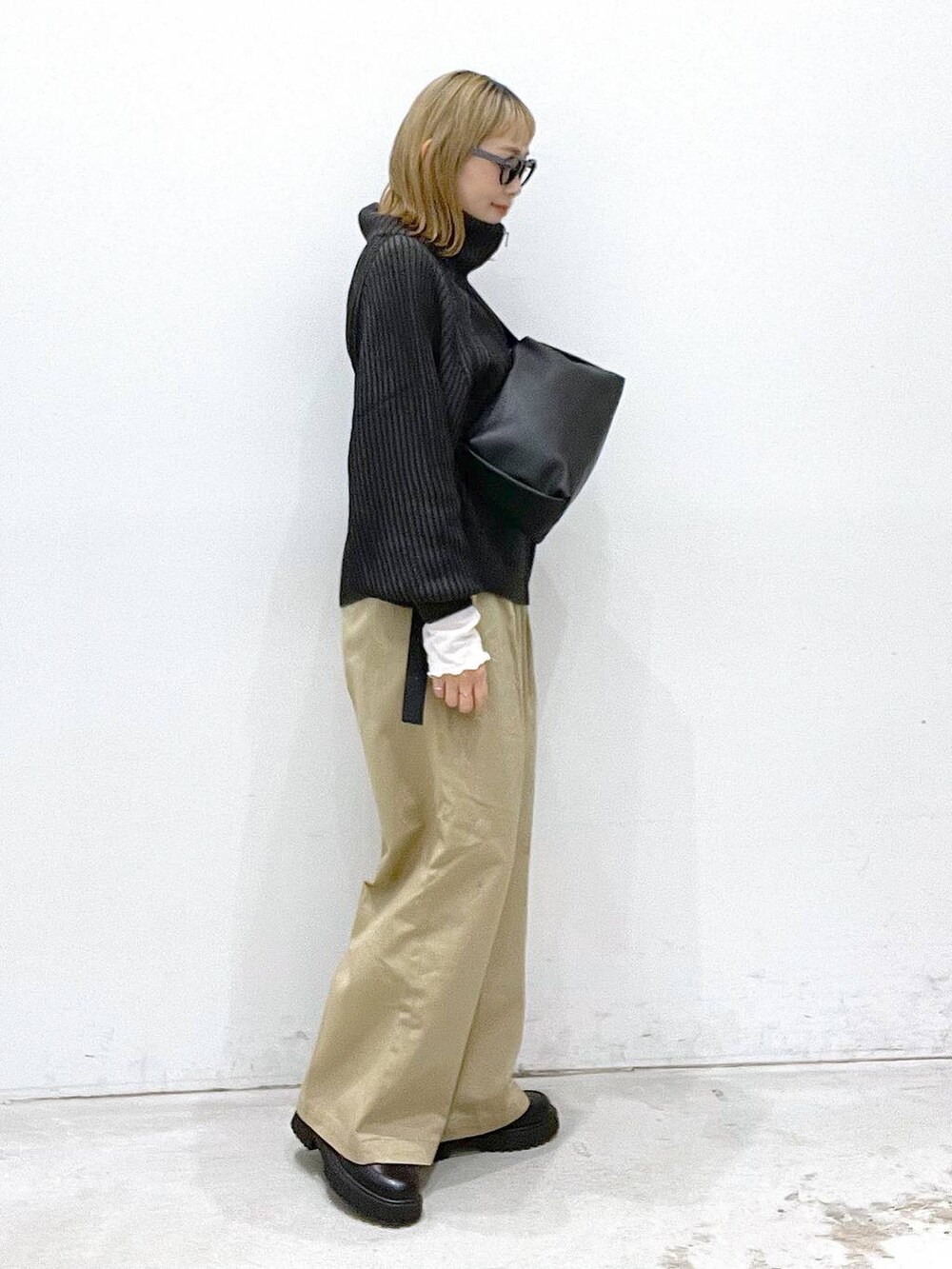 ベージュ系のチノパンツ、ブラック系のブーツ、ブラック系のカーディガン/ボレロを着用したレディースの秋コーディネートの2枚目の写真