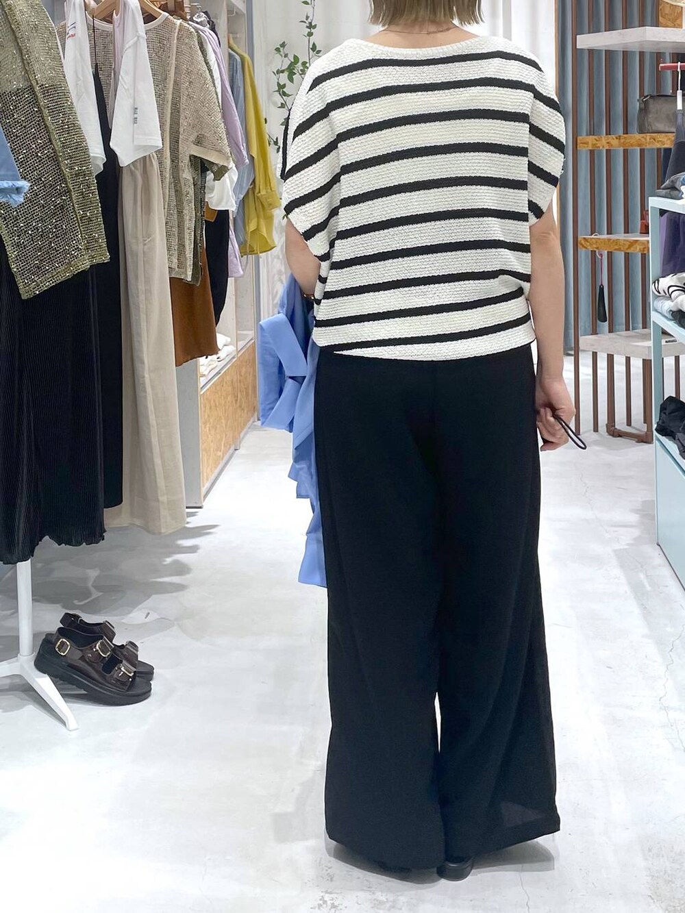 ホワイト系のニット/セーター、ブラック系のその他パンツ、ブルー系のシャツ/ブラウスを着用したレディースの春コーディネートの3枚目の写真