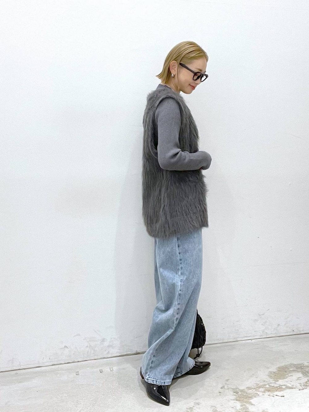 ブラック系のその他シューズ、ブラック系のショルダーバッグ、グレー系のベストを着用したレディースの秋コーディネートの2枚目の写真