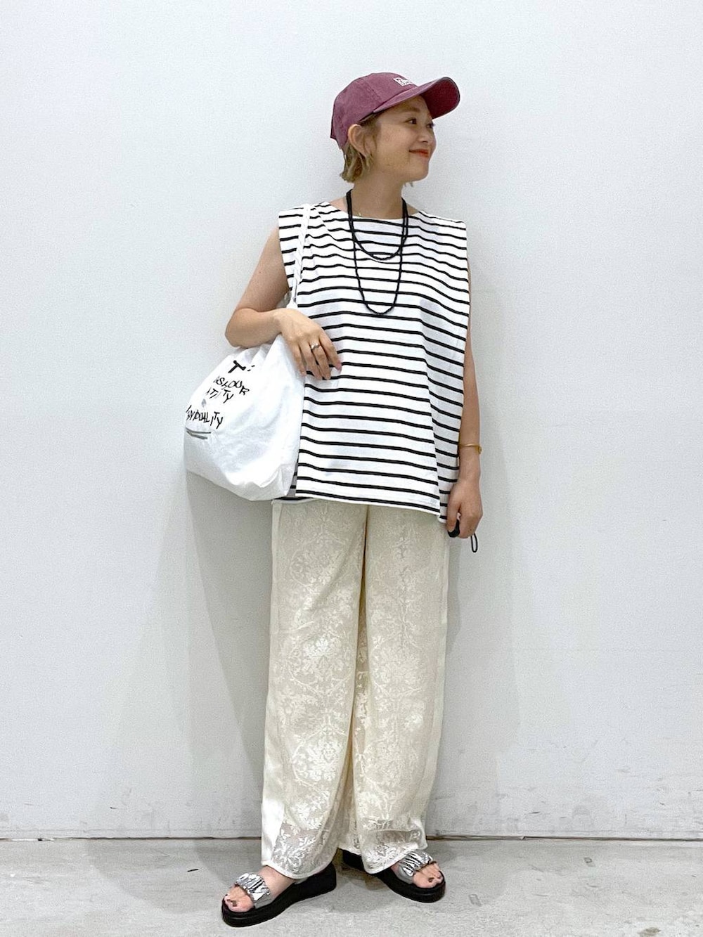 シルバー系のサンダル、ホワイト系のTシャツ/カットソー、ホワイト系のショルダーバッグを着用したレディースの夏コーディネートの3枚目の写真