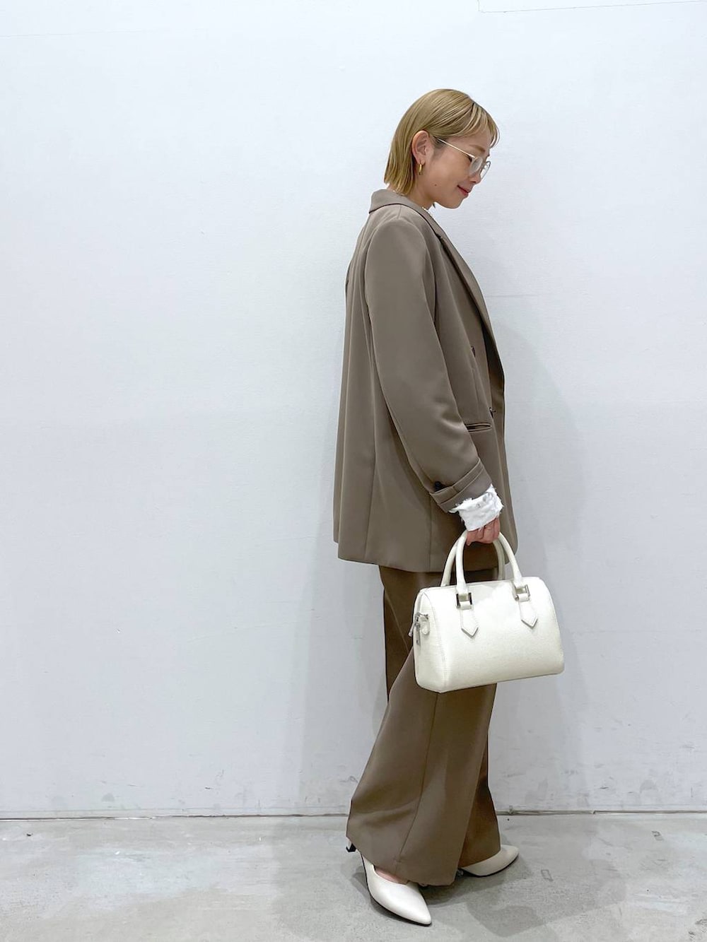 ブラウン系のスーツパンツ、ホワイト系のシャツ/ブラウス、ホワイト系のパンプスを着用したレディースの冬コーディネートの2枚目の写真