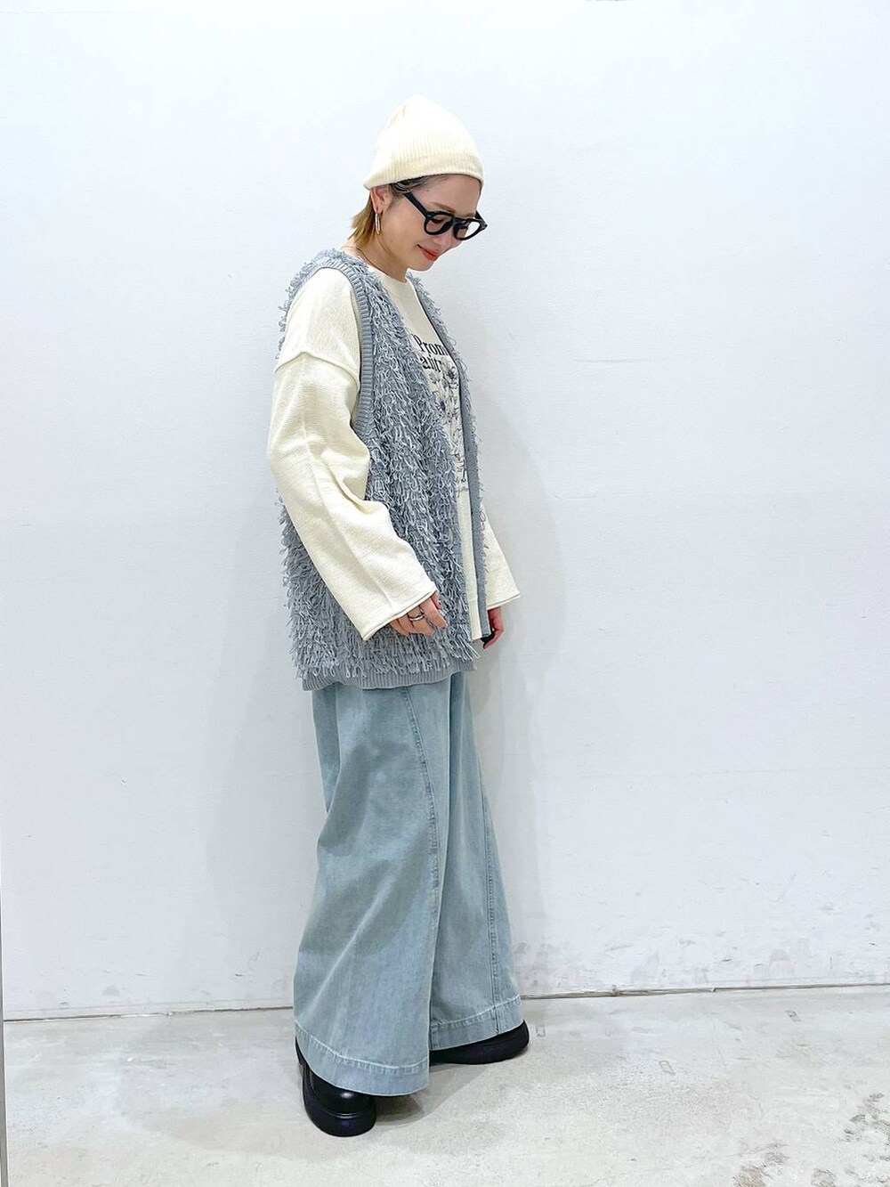 ブルー系のデニムパンツ、ブラック系のサンダル、グレー系のベストを着用したレディースの春コーディネートの2枚目の写真