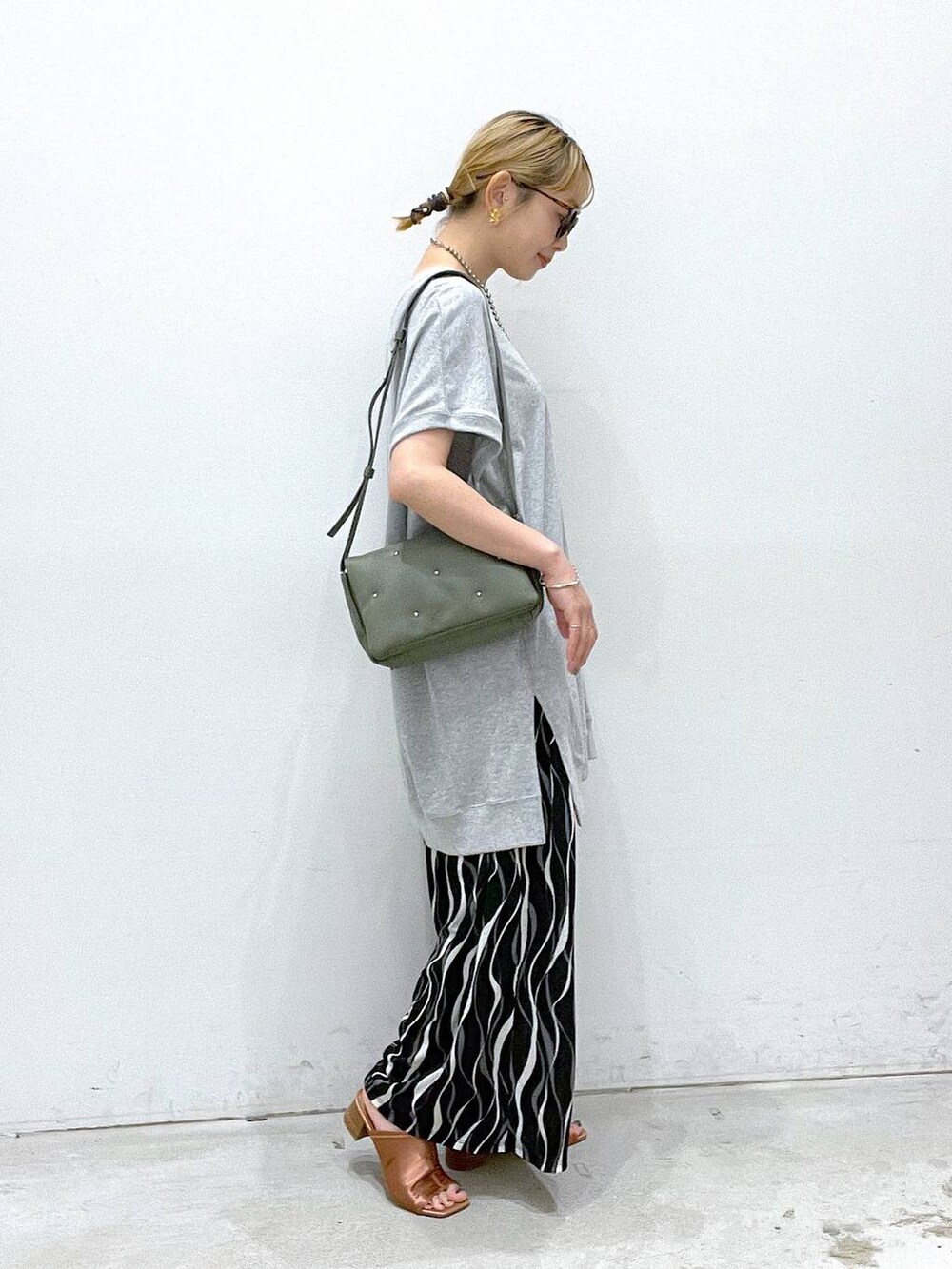 グリーン系のショルダーバッグ、ブラック系のその他パンツ、グレー系のチュニックを着用したレディースの夏コーディネートの2枚目の写真