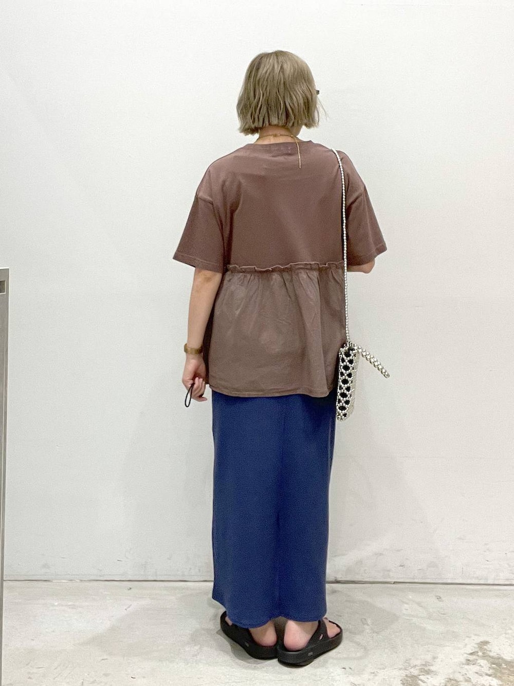 ブルー系のスカート、ブラウン系のTシャツ/カットソー、シルバー系のショルダーバッグを着用したレディースの夏コーディネートの3枚目の写真