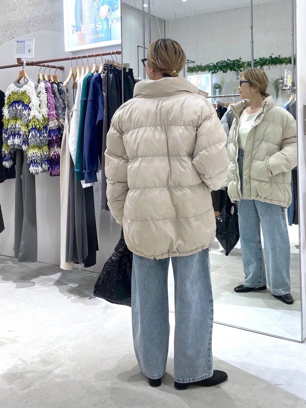 ベージュ系のダウンジャケット/コート、ブラック系のブーツ、ブルー系のデニムパンツを着用したレディースの秋コーディネートの3枚目の写真