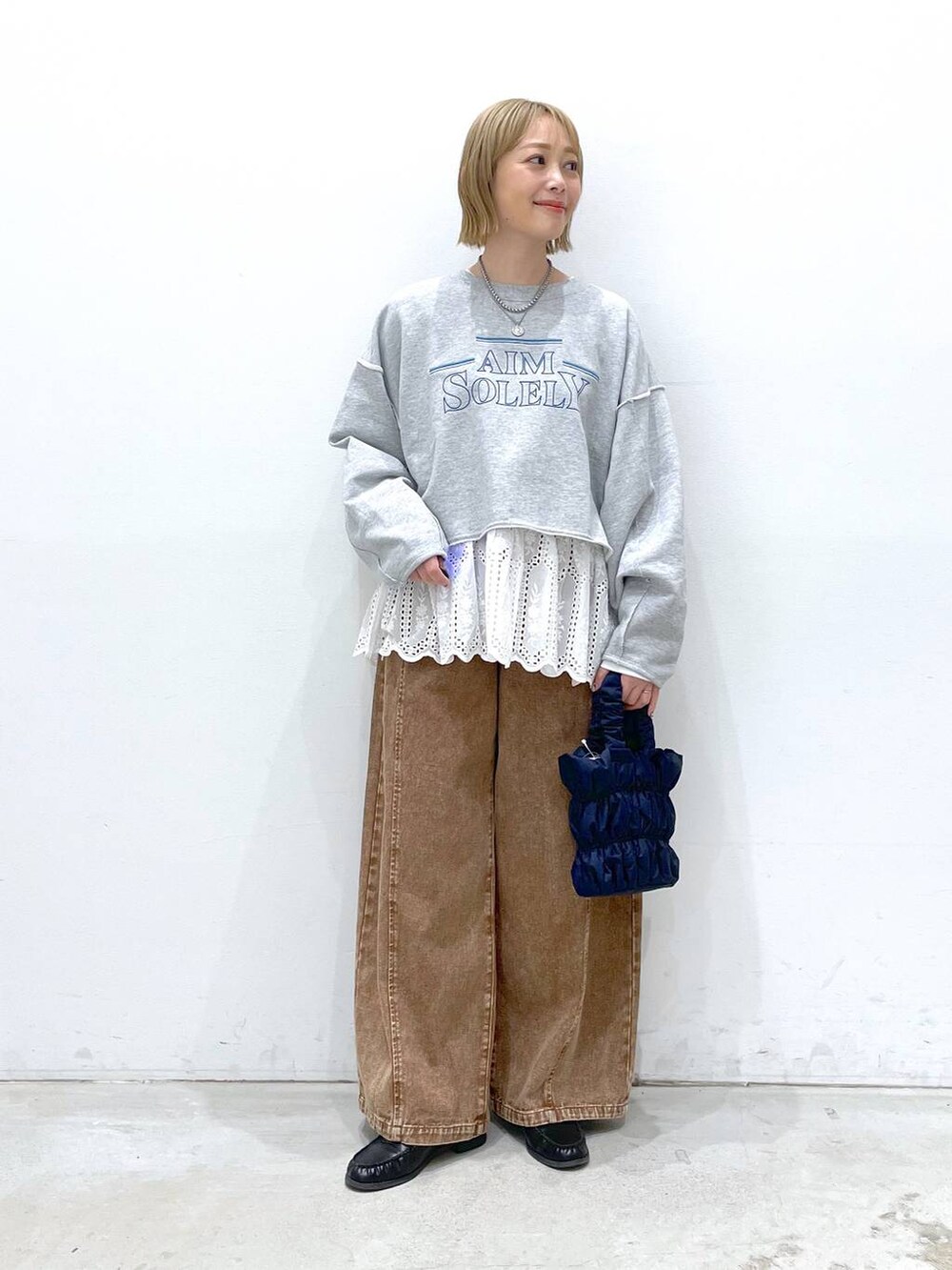 ホワイト系のTシャツ/カットソー、ブルー系のショルダーバッグ、ブラウン系のデニムパンツを着用したレディースの冬コーディネートの2枚目の写真