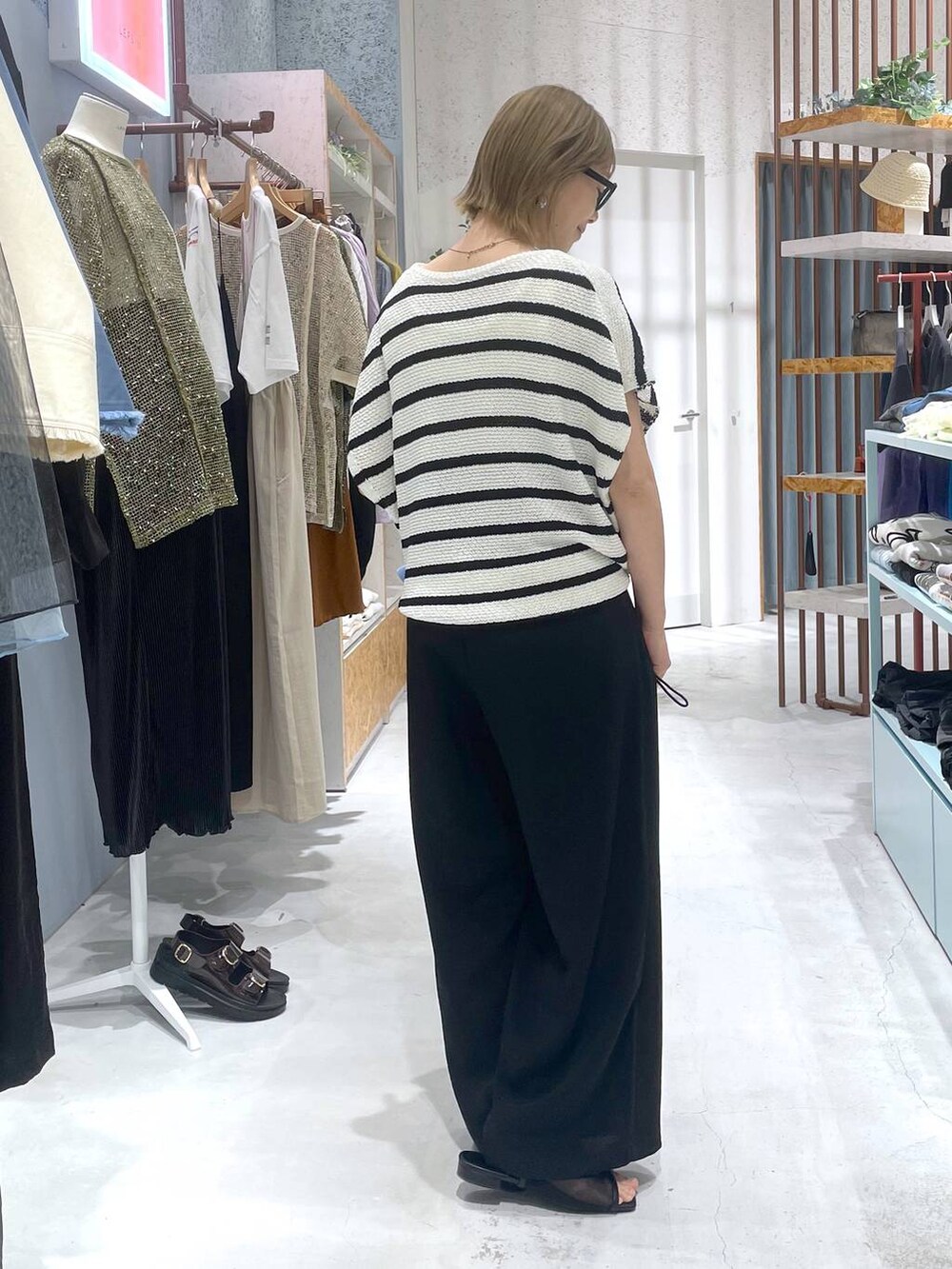 ホワイト系のニット/セーター、ブラック系のその他パンツ、ブルー系のシャツ/ブラウスを着用したレディースの春コーディネートの2枚目の写真