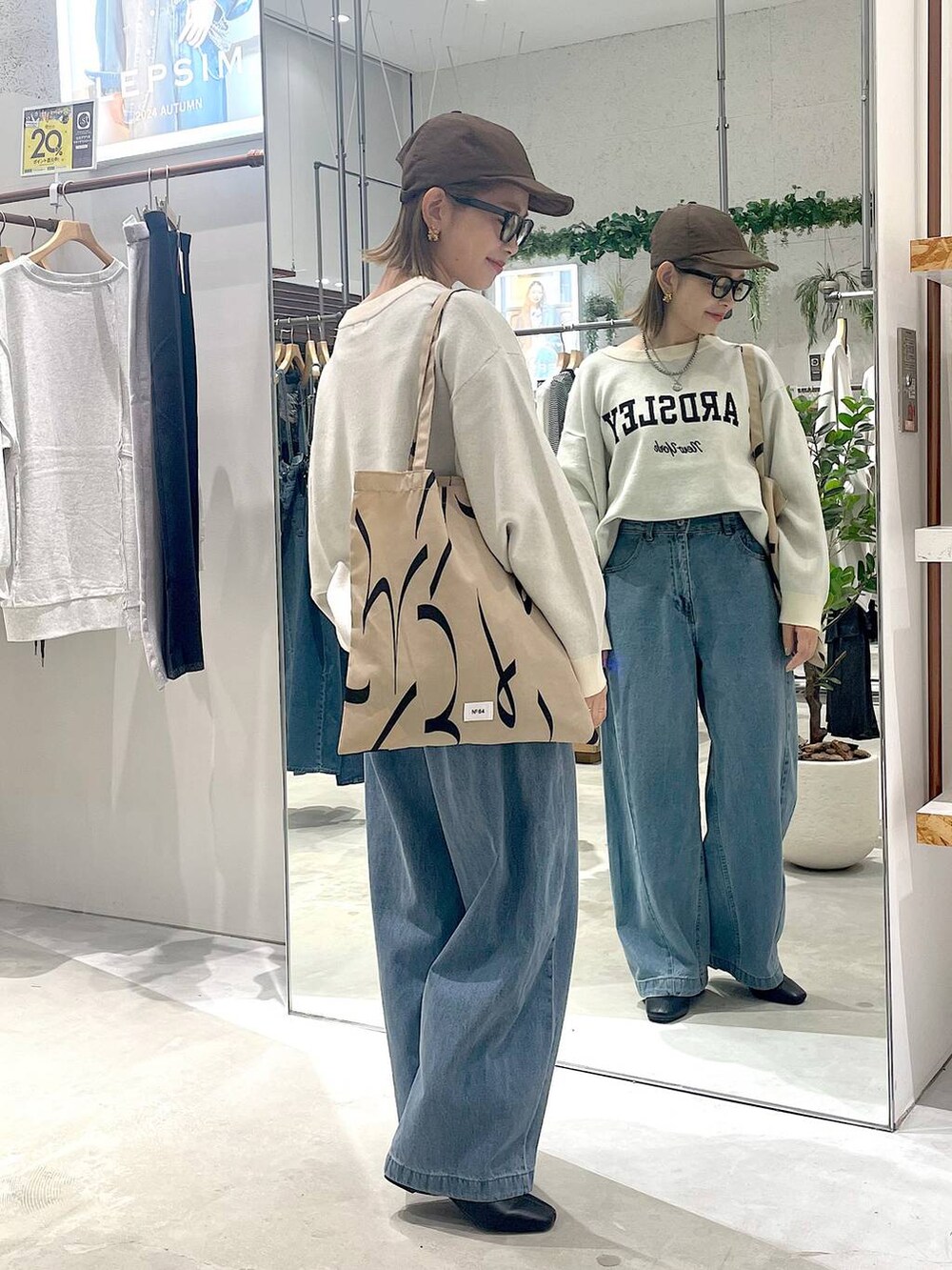 ブラウン系のトートバッグ、ブルー系のデニムパンツ、ホワイト系のニット/セーターを着用したレディースの秋コーディネートの2枚目の写真