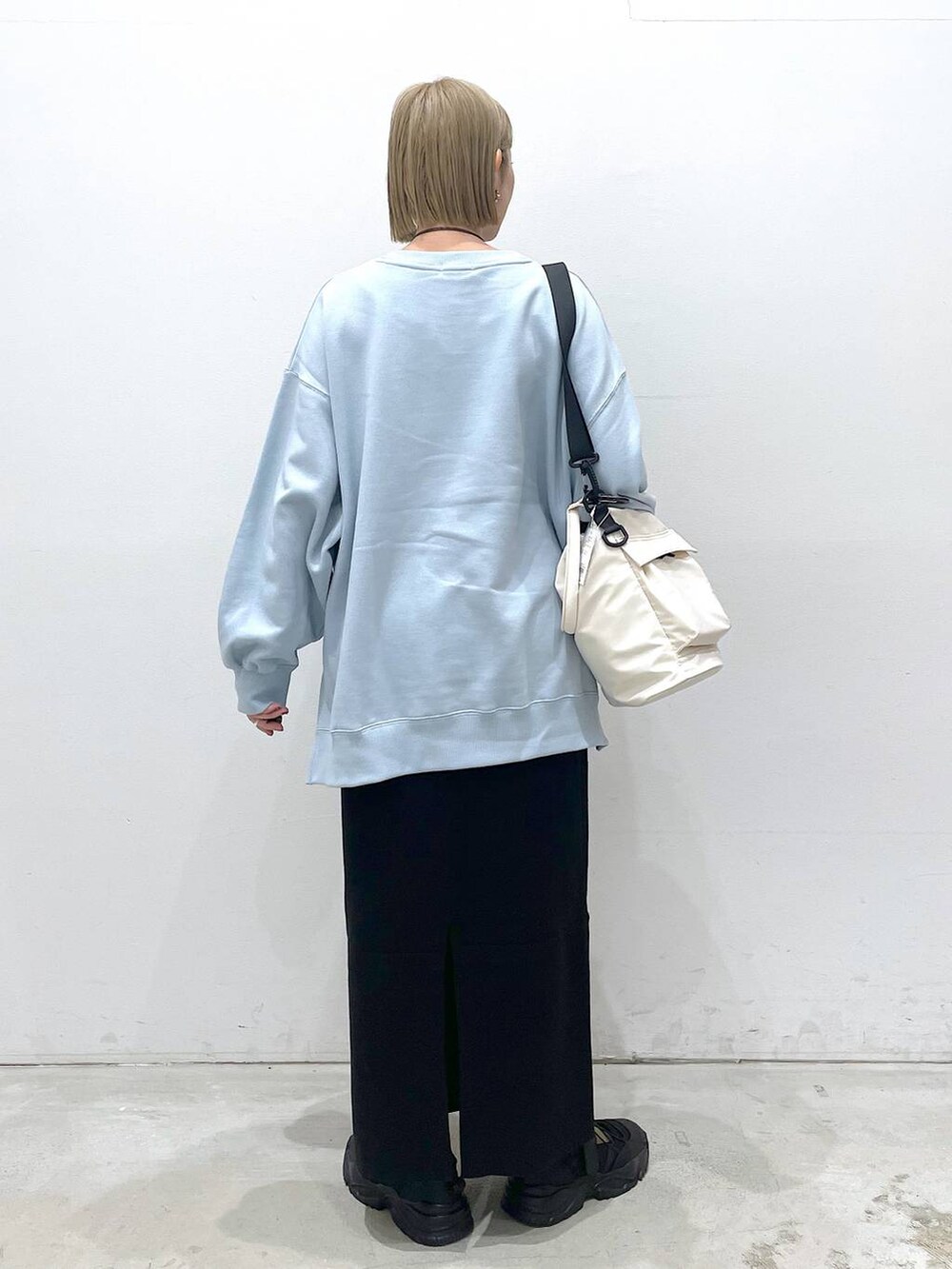 ホワイト系のショルダーバッグ、ブラック系のスカート、ブラック系のスニーカーを着用したレディースの冬コーディネートの3枚目の写真